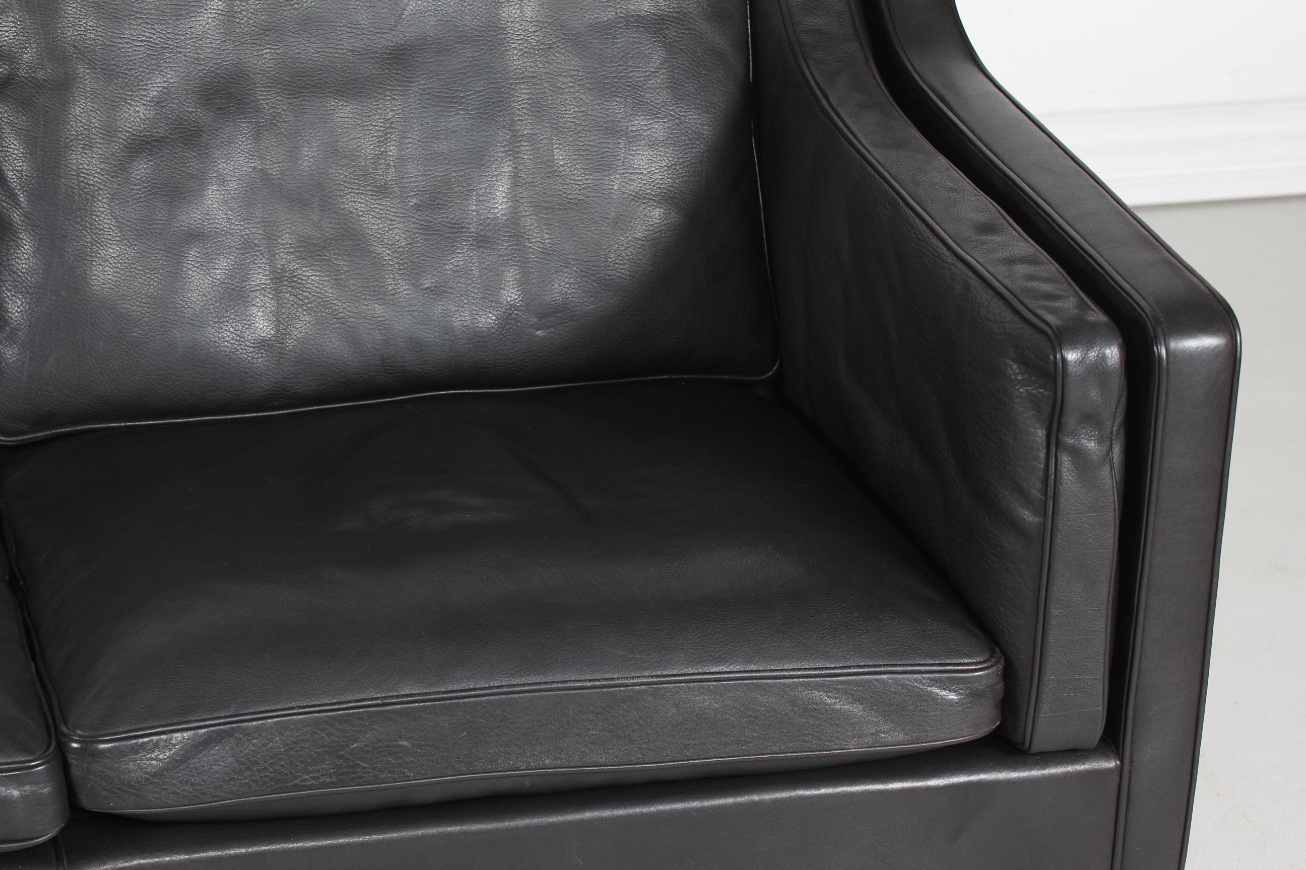 Danish vintage Børge Mogensen sofa for 2 persons model 2212.
It's upholstered with the original black leather. The legs are made of mahogany. 
The cushions are filled inside with granules and natural feathers which gives the sofa a very good
