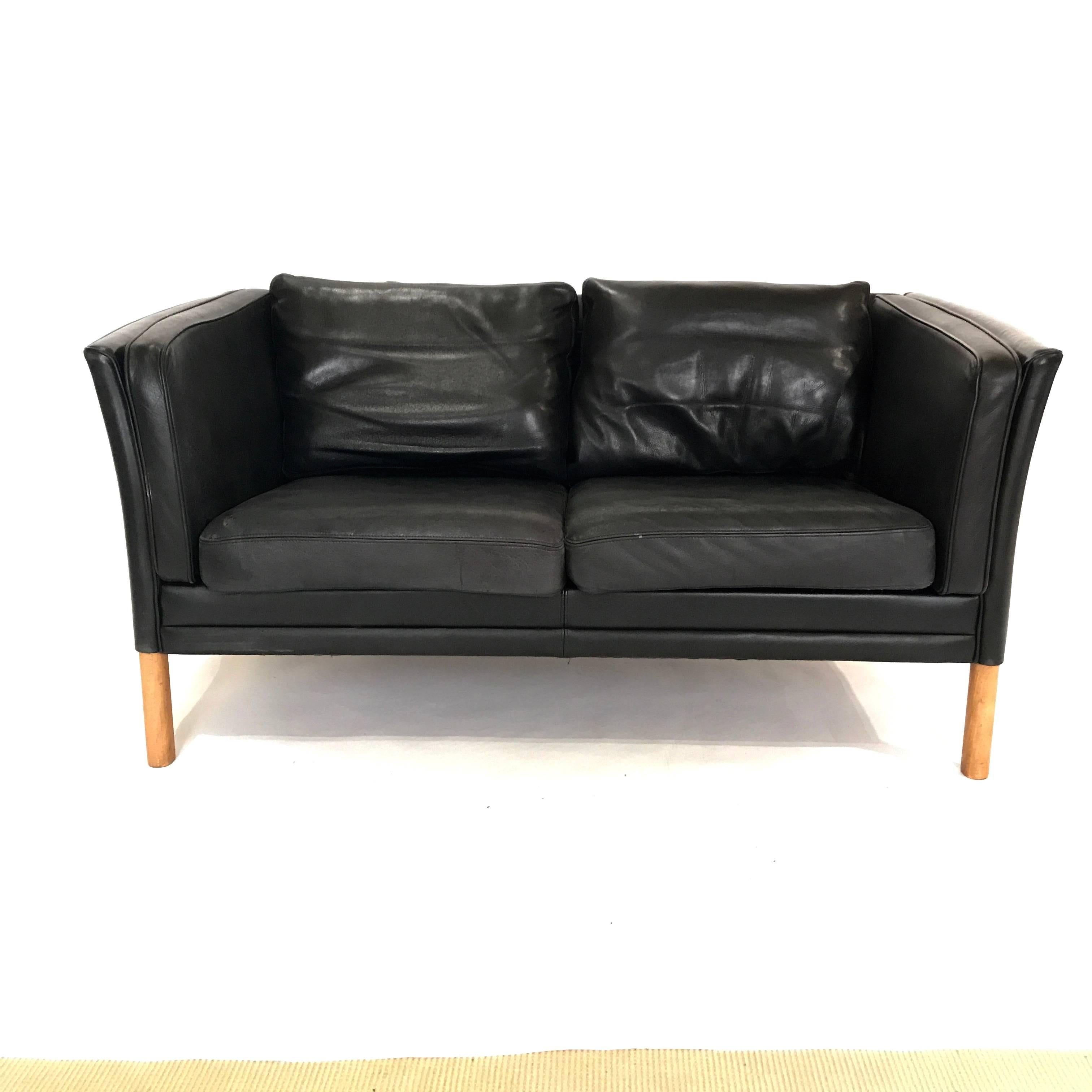 Two-seat black leather sofa from Denmark in the manner of Børge Mogensen. Beautiful patinated black leather with solid beech wood legs. Stunning Danish design.