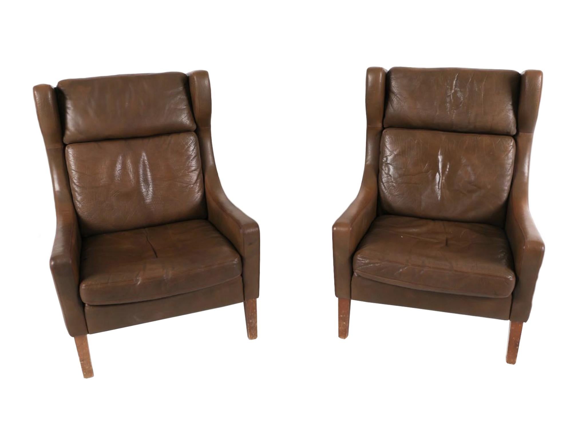 Made in the 1970s, these armchairs with matching ottomans were designed in the style of Børge Mogensen. They have a rich brown leather upholstery and beech legs. Each chair has three removable cushions, while each ottoman has a single removable