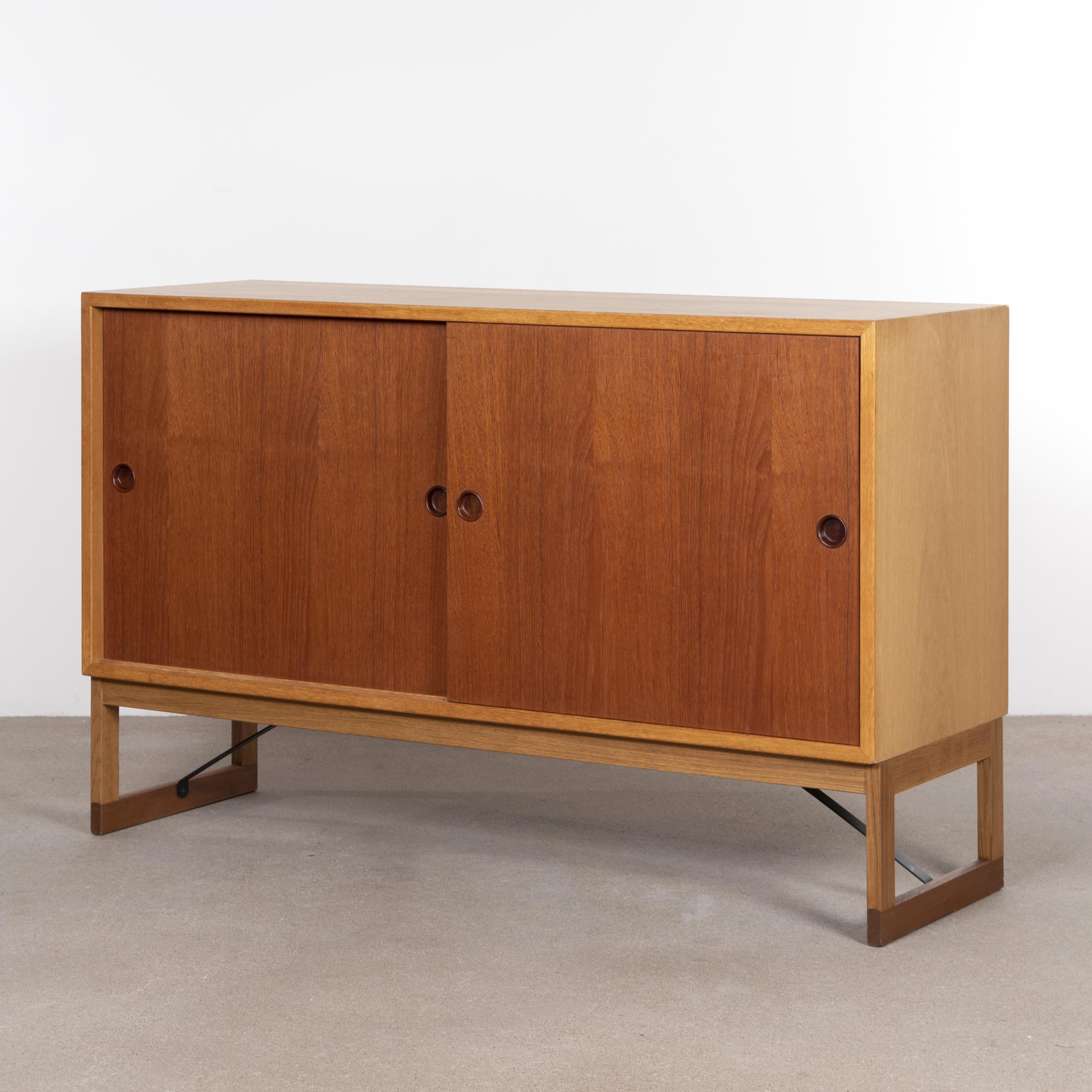 Elegant cabinet by Børge Mogensen for Karl Andersson & Soner. Oak corpus with teak sliding doors (both directions) and glides. Shelves can be moved as required. All in good vintage condition with minor traces of use. A matching set is available.