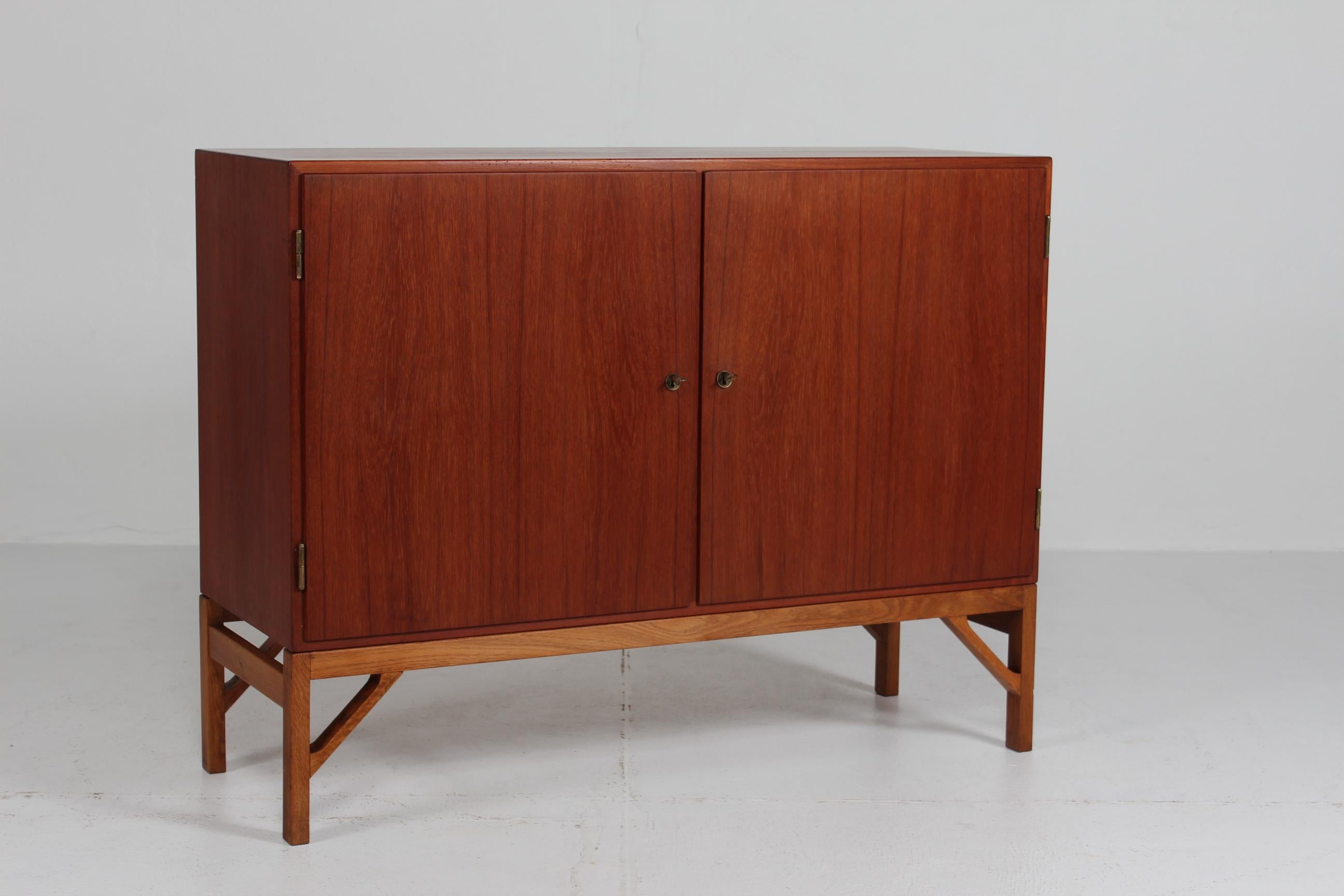 Credenza dell'architetto danese Børge Mogensen (1914-1972) con gambe in porcellana e 2 ante, cassetti interni e ripiani regolabili.

Il mobile è realizzato in teak all'esterno, la struttura e le gambe in rovere massiccio.
All'interno, i cassetti e i