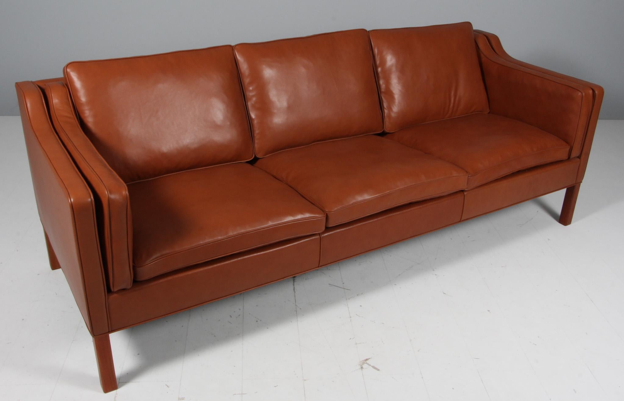 Børge Mogensen three-seat sofa new upholstered with cognac pure aniline leather.

Legs of teak.

Model 2213, made by Fredericia Furniture.