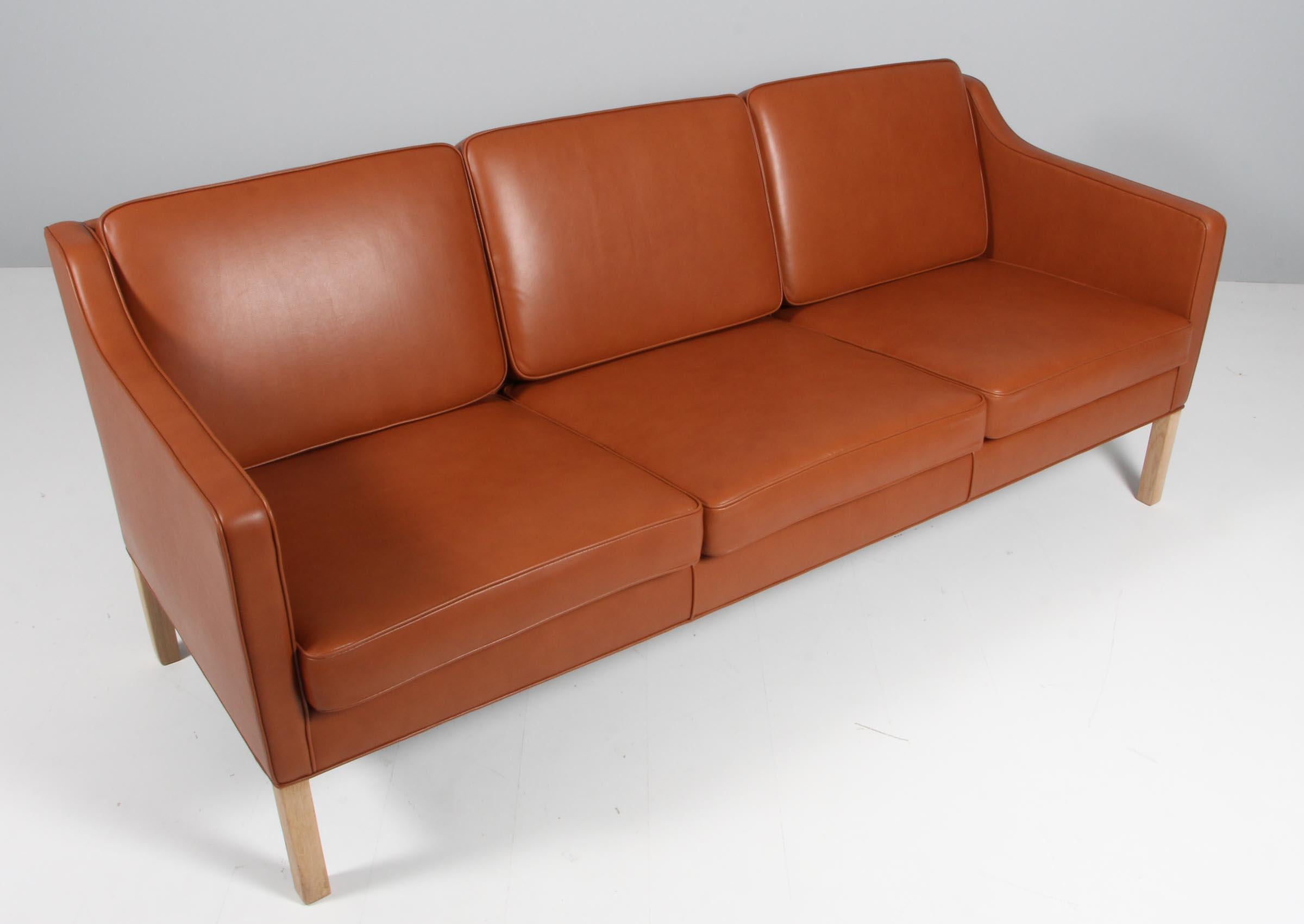 Børge Mogensen three-seat sofa new upholstered with cognac pure aniline leather.

Legs of soap treated oak.

Model 2323, made by Fredericia Furniture.
