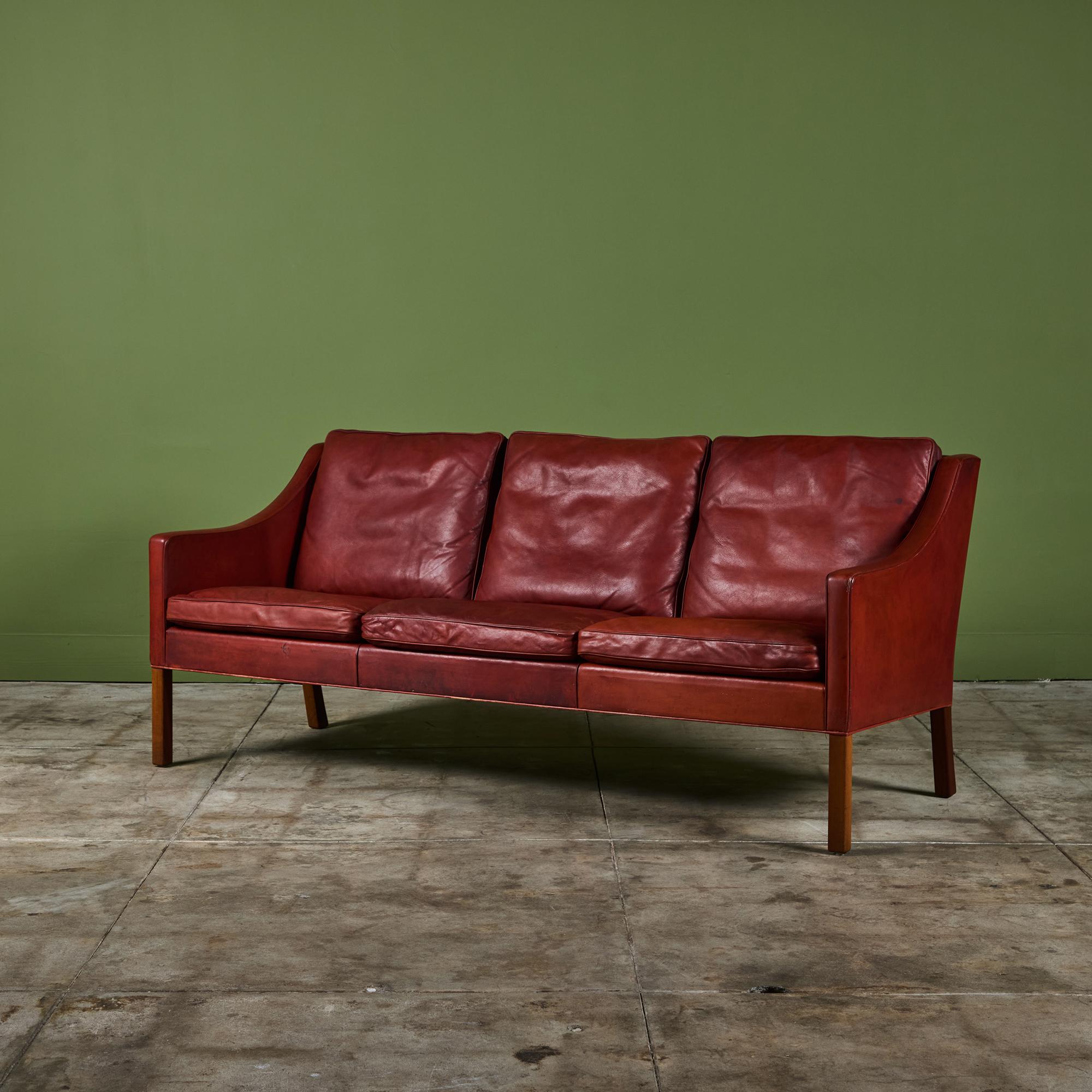 Børge Mogensen sofa for Fredericia Stolefabrik, Denmark, c.1950s. This three seater sofa features the original oxblood red leather upholstery with back cushions and curved arm rests supported by four mahogany legs.

Dimensions
73