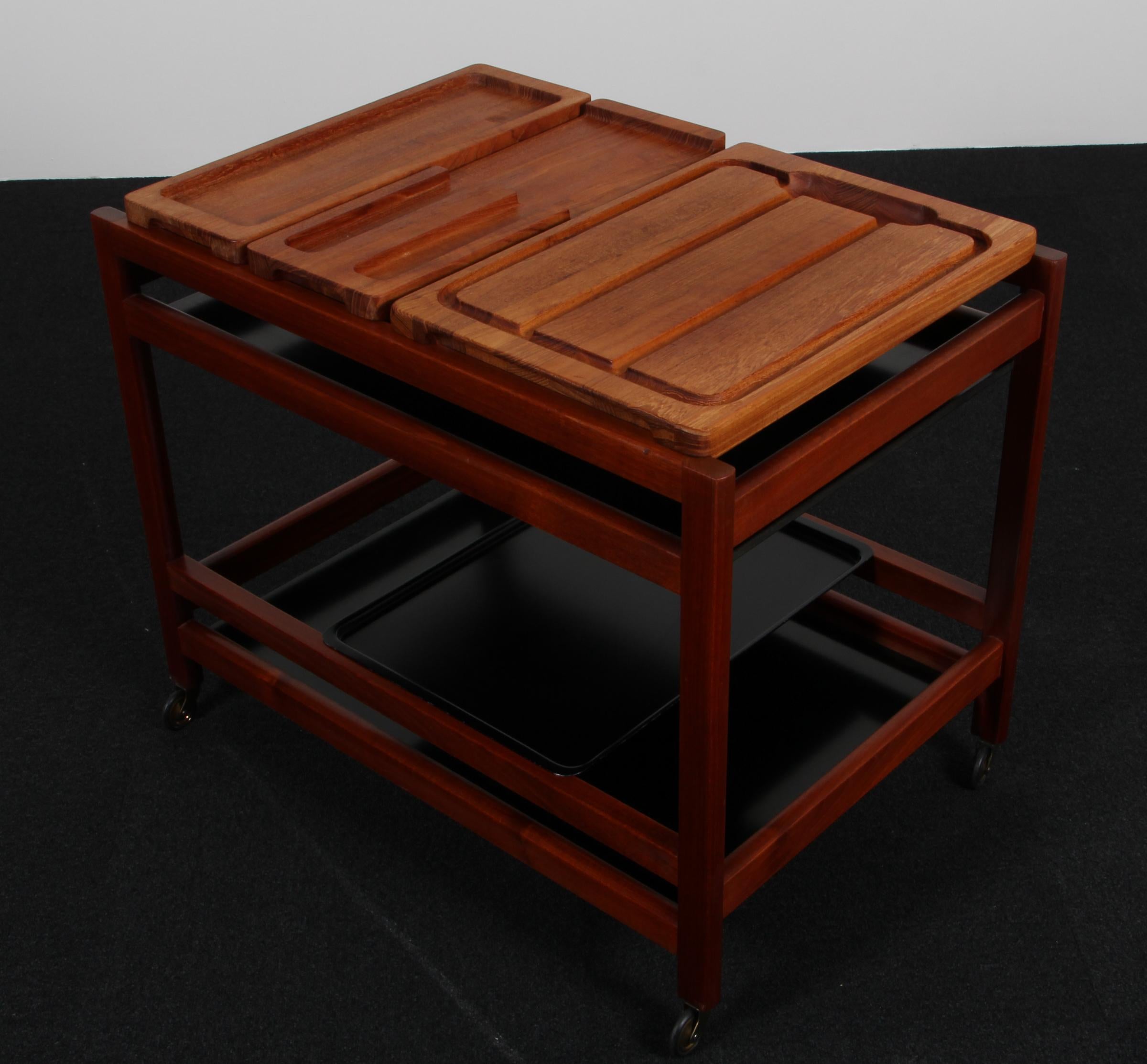 Mesa bandeja Børge Mogensen con armazón de caoba. Placas de laminado negro. Con tabla de cortar, etc.

Montado sobre ruedas.

Modelo 5370, fabricado por Fredericia Furniture.