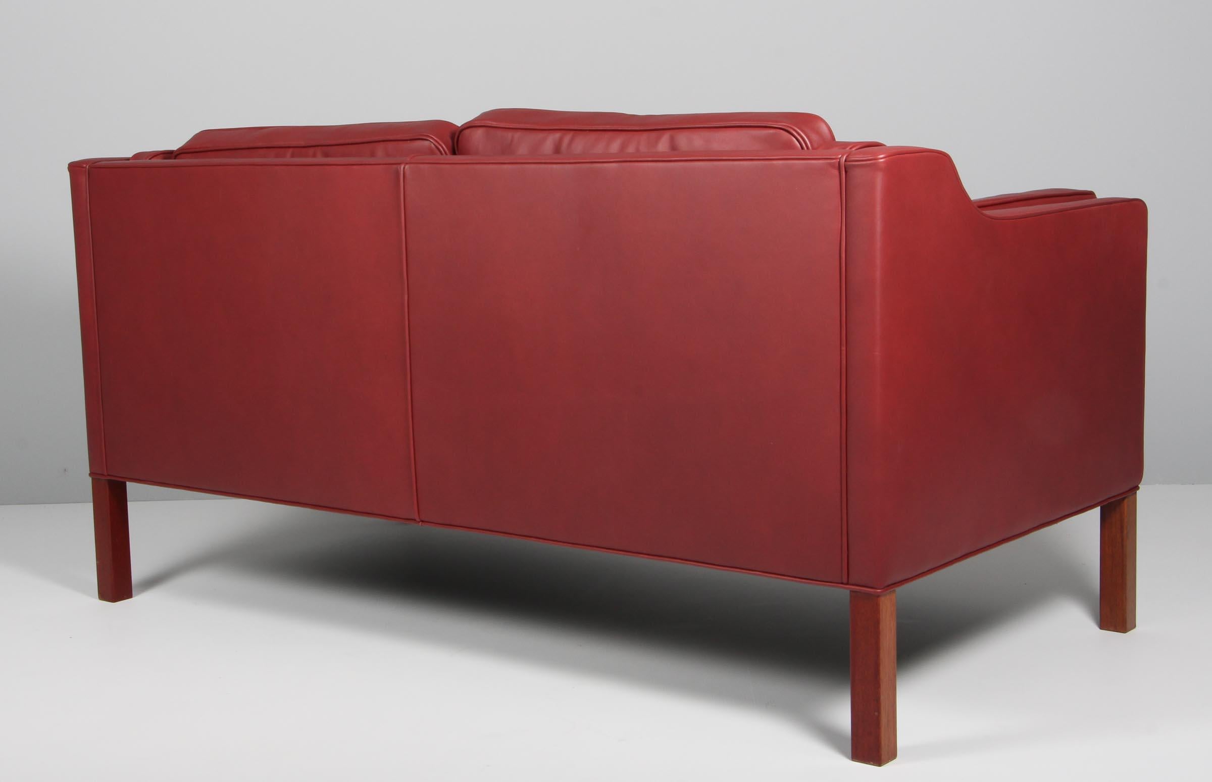 Canapé deux places Børge Mogensen, neuf, recouvert de cuir aniline rouge indien élégant.

Pieds en acajou.

Modèle 2212, fabriqué par Fredericia Furniture.