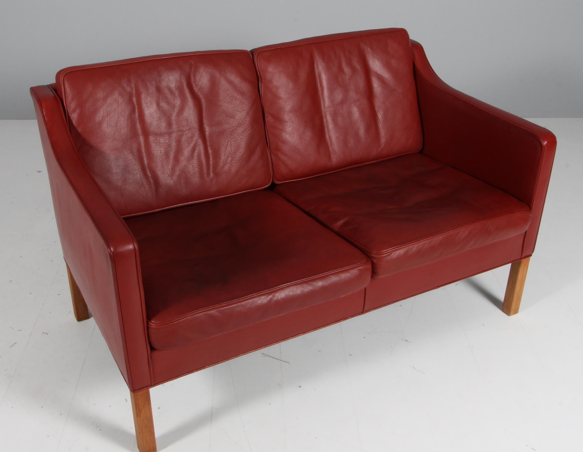 Børge Mogensen two-seat sofa original upholstered with red/brown leather.

Legs of oak.

Model 2322, made by Fredericia Furniture.