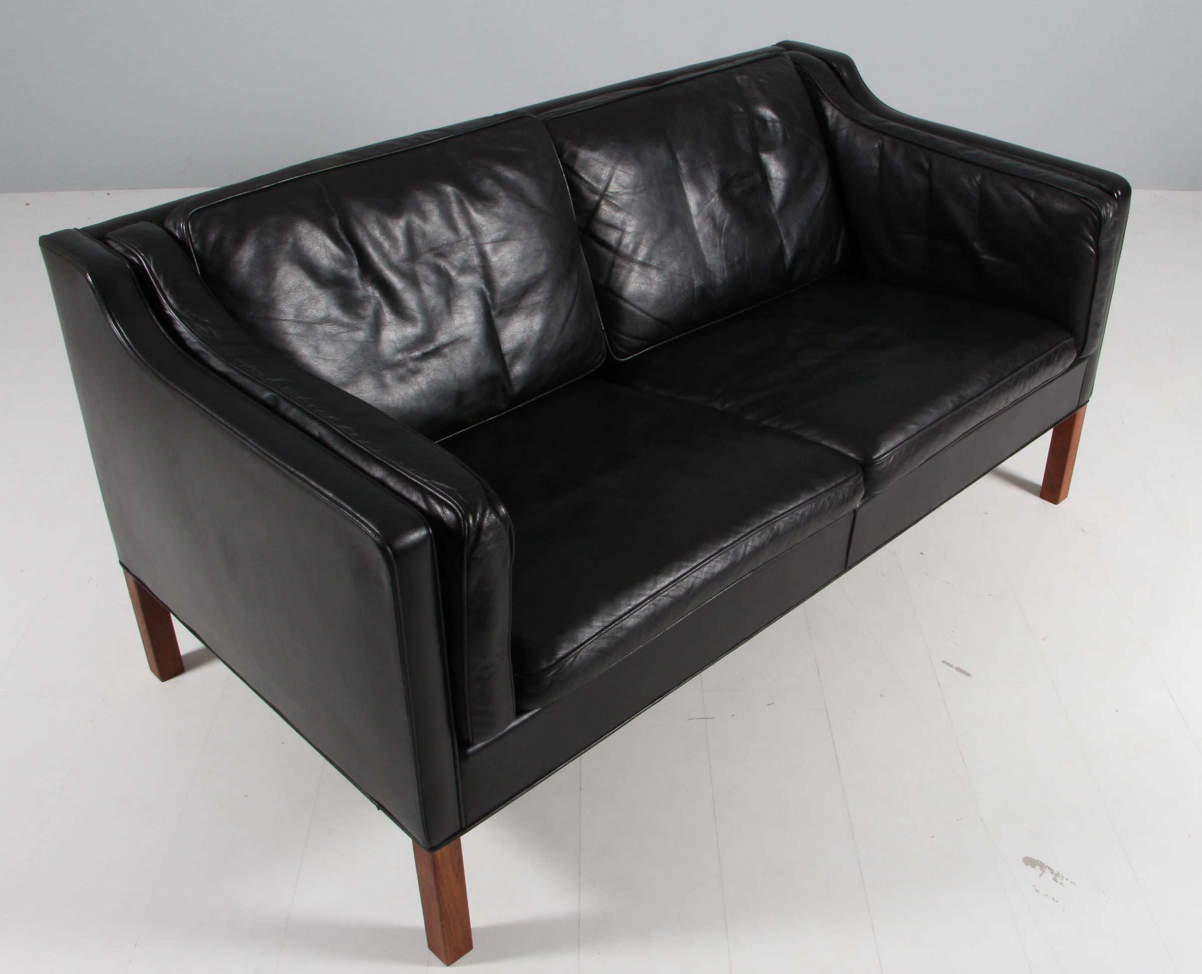 Børge Mogensen two-seat sofa with original patinated black leather upholstery.

Legs of teak.

Model 2212, made by Fredericia Furniture.

Matching three seater in stock.