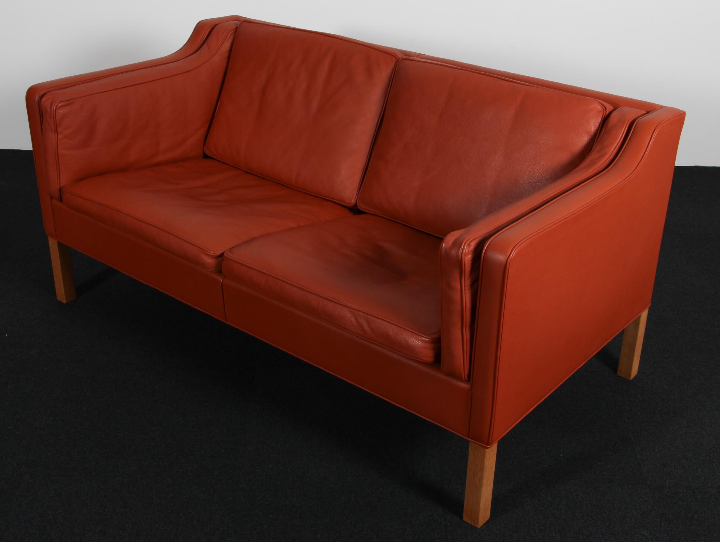 Canapé deux places Børge Mogensen avec revêtement d'origine en cuir rouge et brun.

Pieds en chêne.

Modèle 2212, fabriqué par Fredericia Furniture.

Trois places assorties


