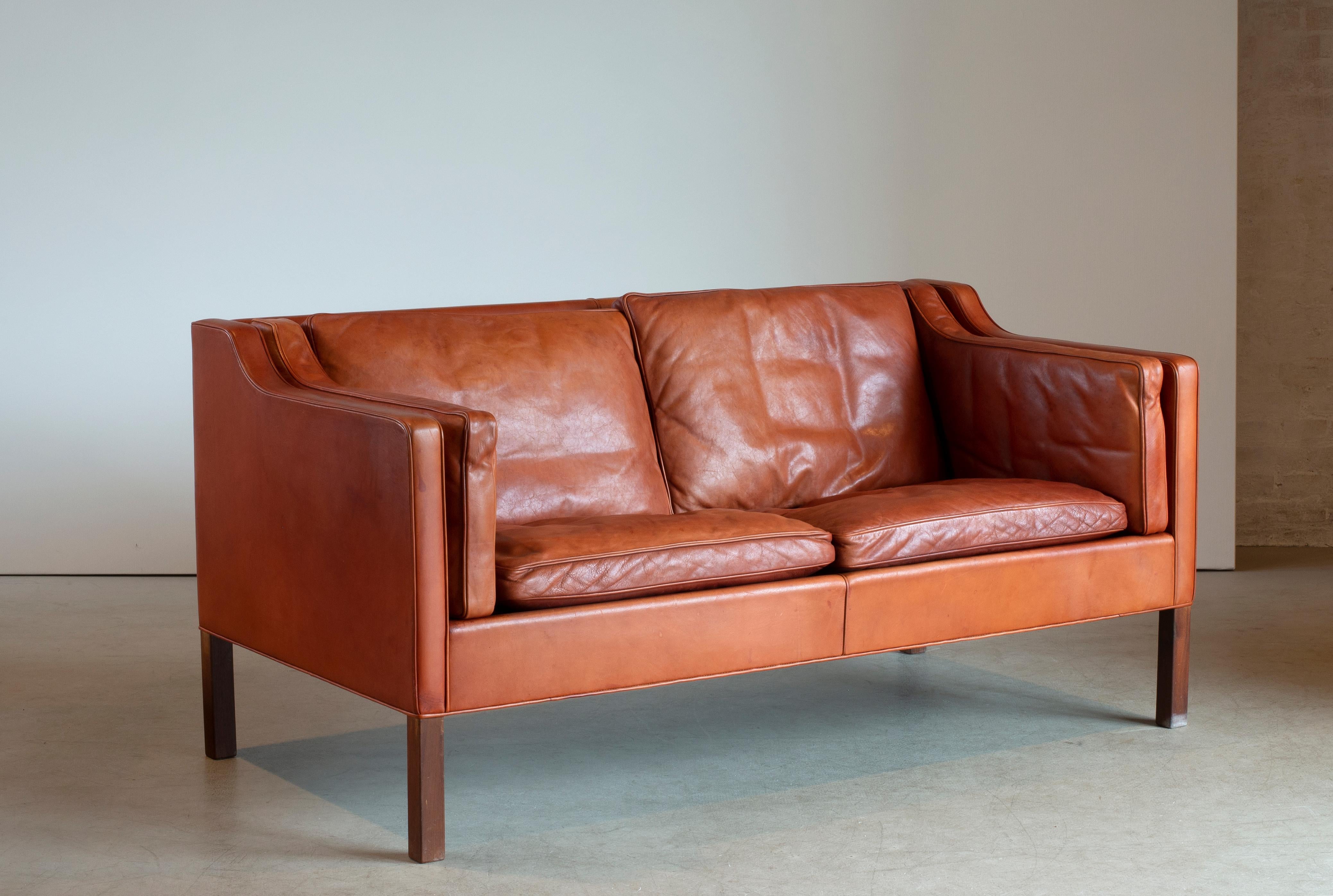 Børge Mogensen freestanding two seater sofa mounted on walnut legs. Sides, back and loose cushions upholstered with natural tanned leather. Manufactured by Fredericia Furniture in 1974.