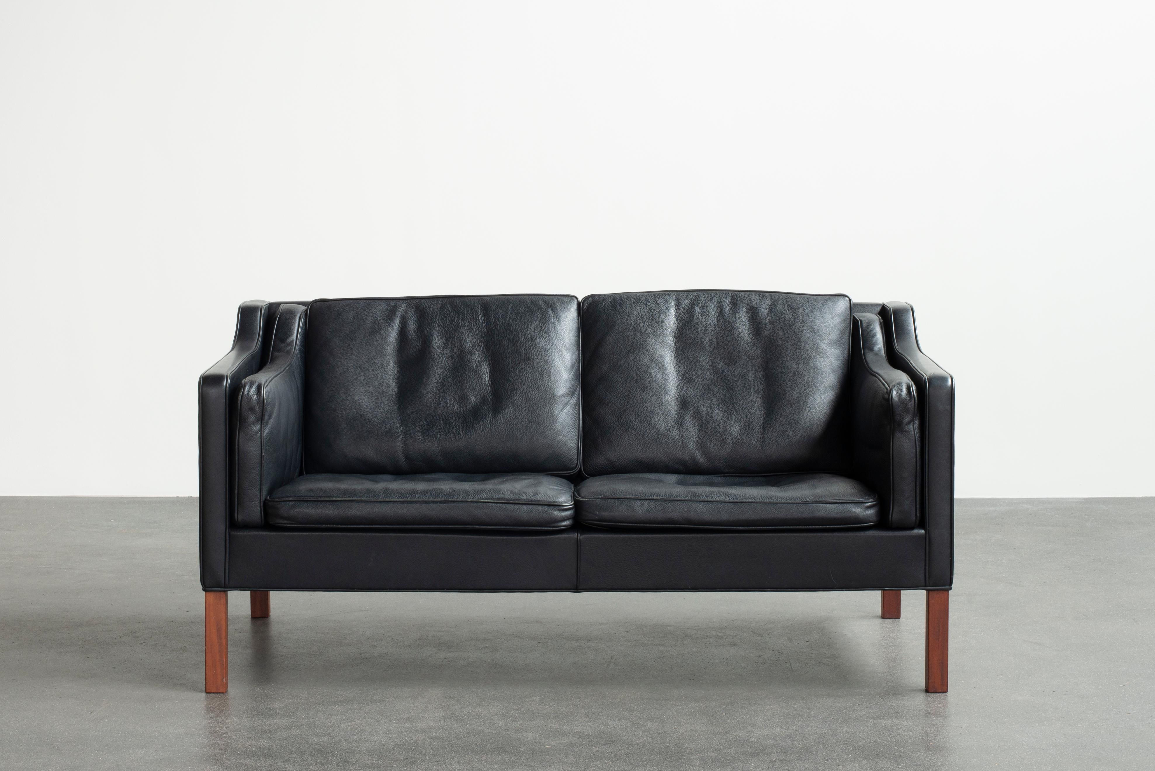 Børge Mogensen freestanding two seater sofa mounted on Mahogany legs. Sides, back and loose cushions upholstered with black leather. Manufactured by Fredericia Furniture in 1985.