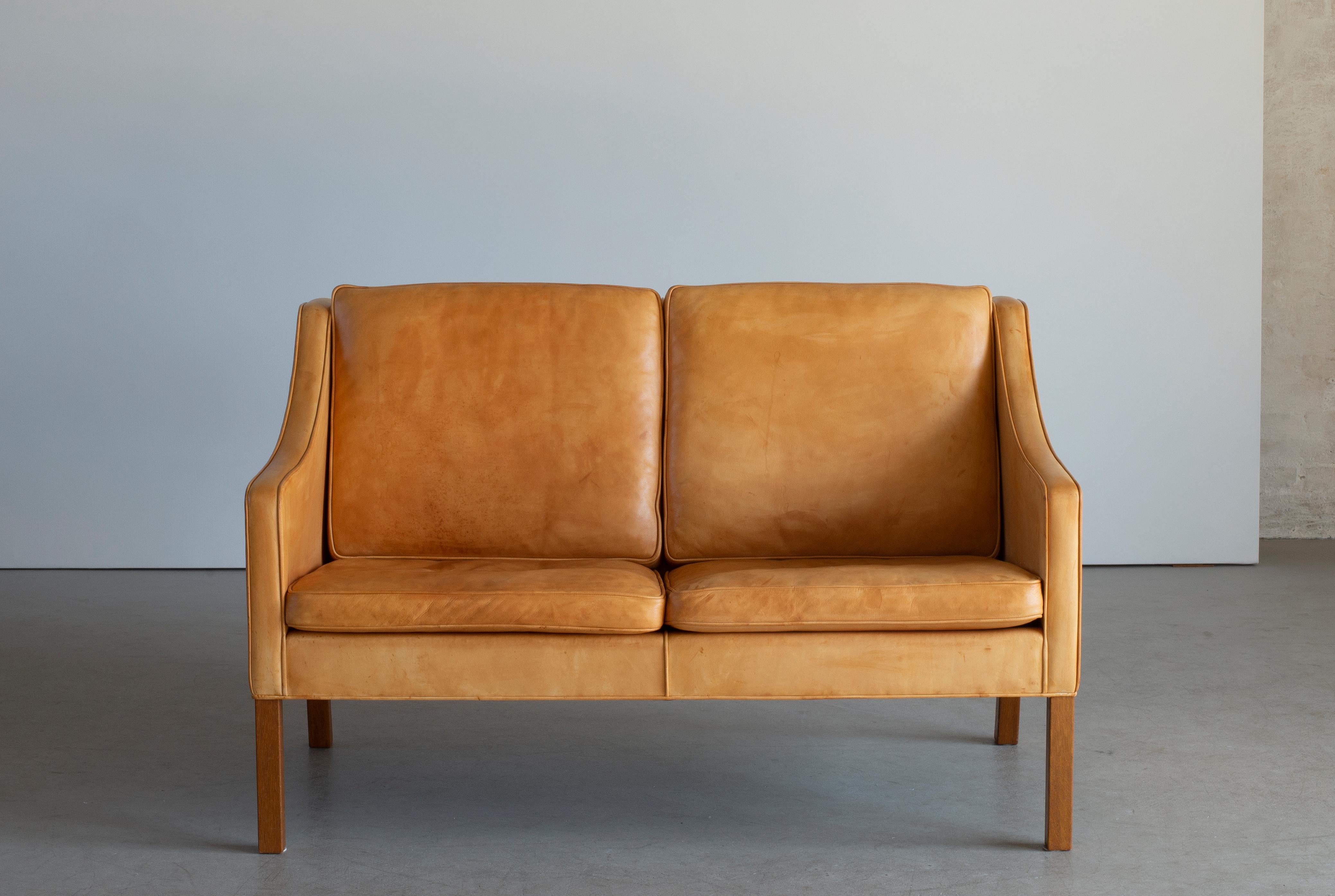 Freestanding two seater sofa with legs of oak. Sides, back and loose cushions upholstered with natural tanned ox-hide. Model 2208. Manufactured and marked by Fredericia Stolefabrik.