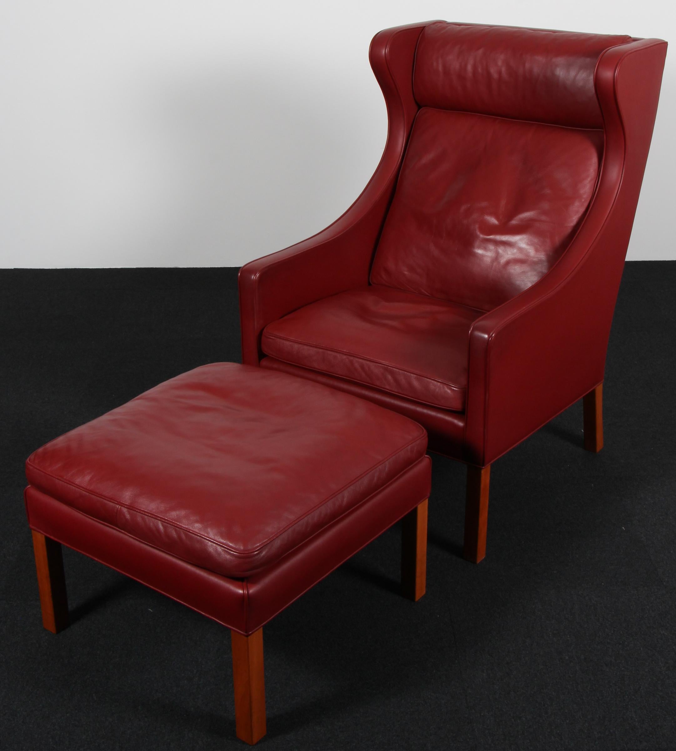 Fauteuil à oreilles et ottoman Børge Mogensen, recouvert de cuir rouge. 

Pieds en teck.

Modèles 2202 et 2204, fabriqués par Fredericia Furniture.
