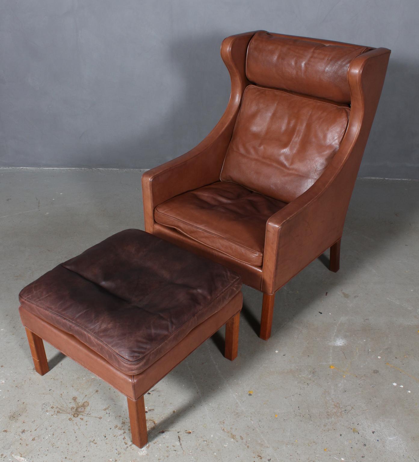 Børge Mogensen wingback chair and ottoman original upholstered with leather.

Legs of teak.

Model 2202 and 2204, made by Fredericia Furniture.