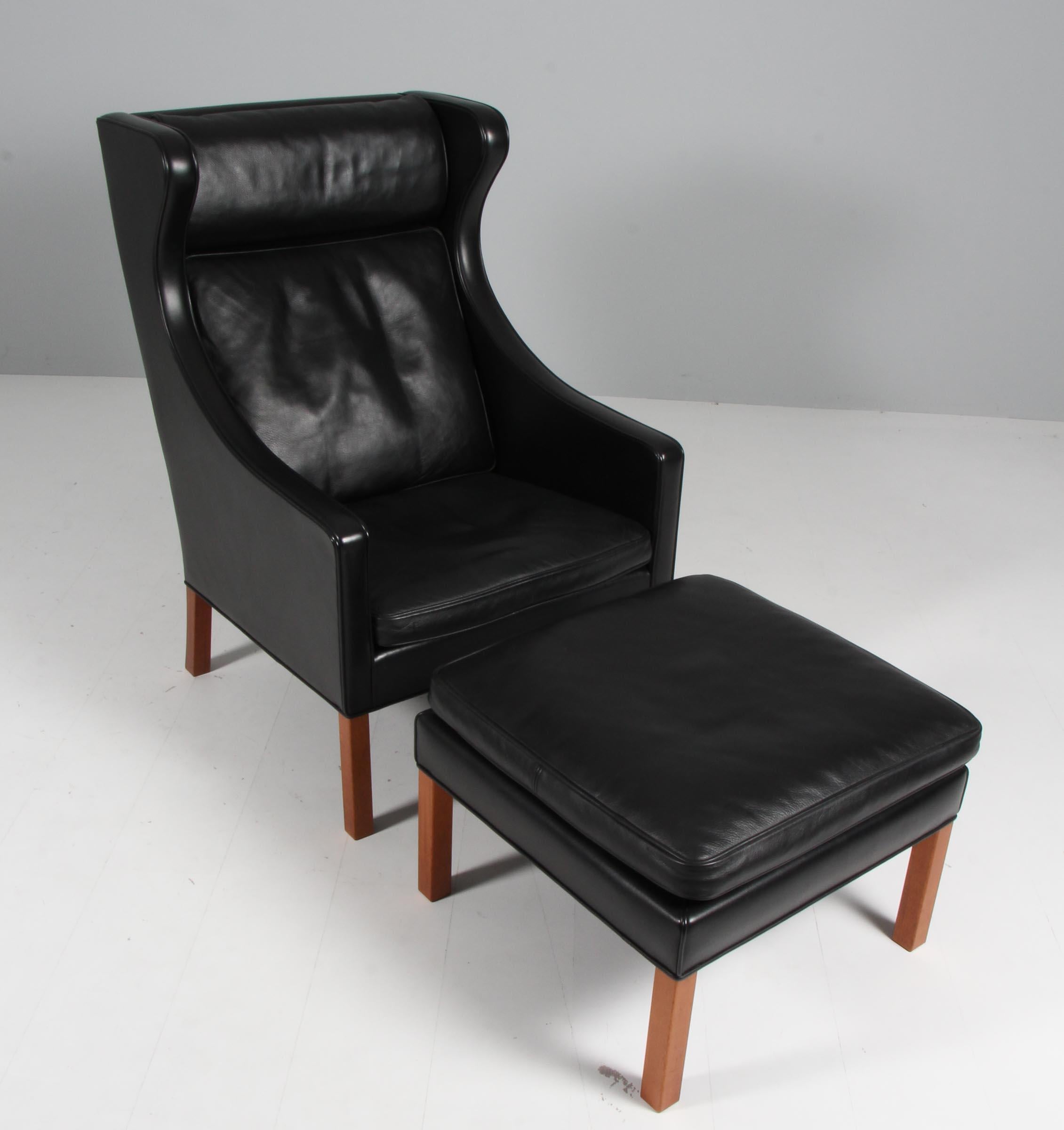 Børge Mogensen wingback chair and ottoman original upholstered with black leather.

Legs of teak.

Model 2202 and 2204, made by Fredericia Furniture.