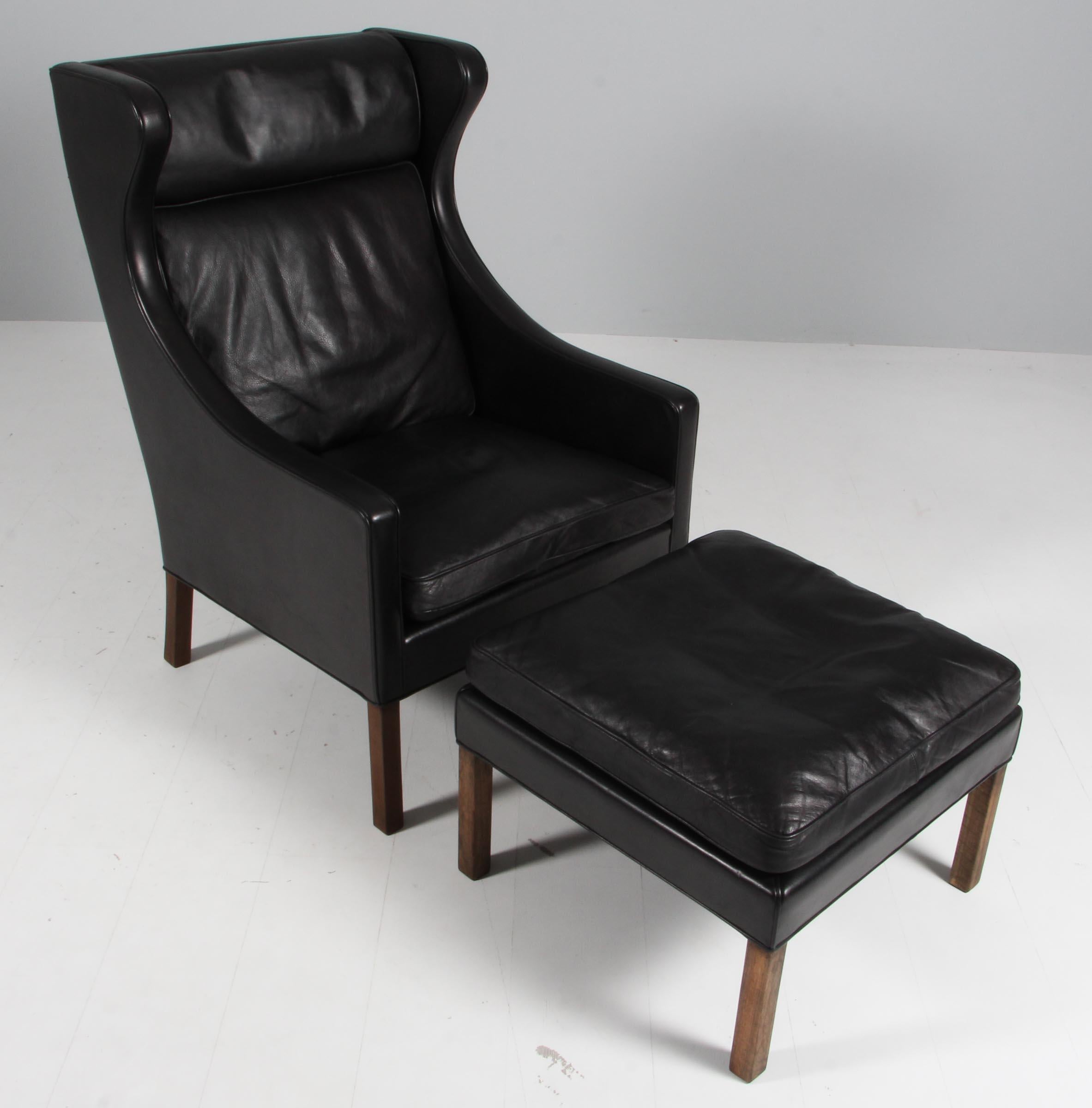 Børge Mogensen wingback chair and ottoman original upholstered with black leather.

Legs of stained wood.

Model 2202 and 2204, made by Fredericia Furniture.