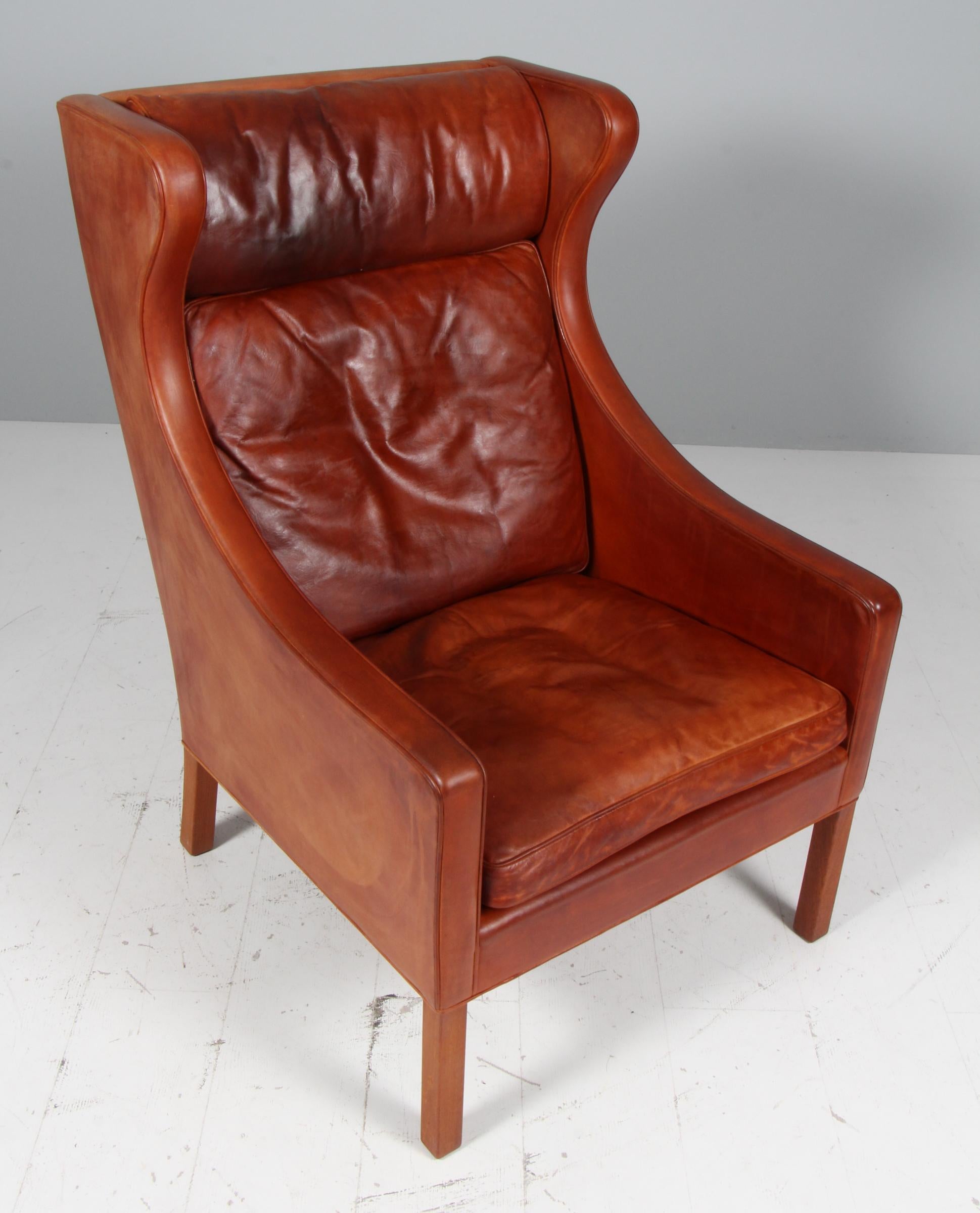 Børge Mogensen wingback chair in original patinated nature leather upholstery.

Legs in teak.

Model 2204, made by Fredericia Furniture.