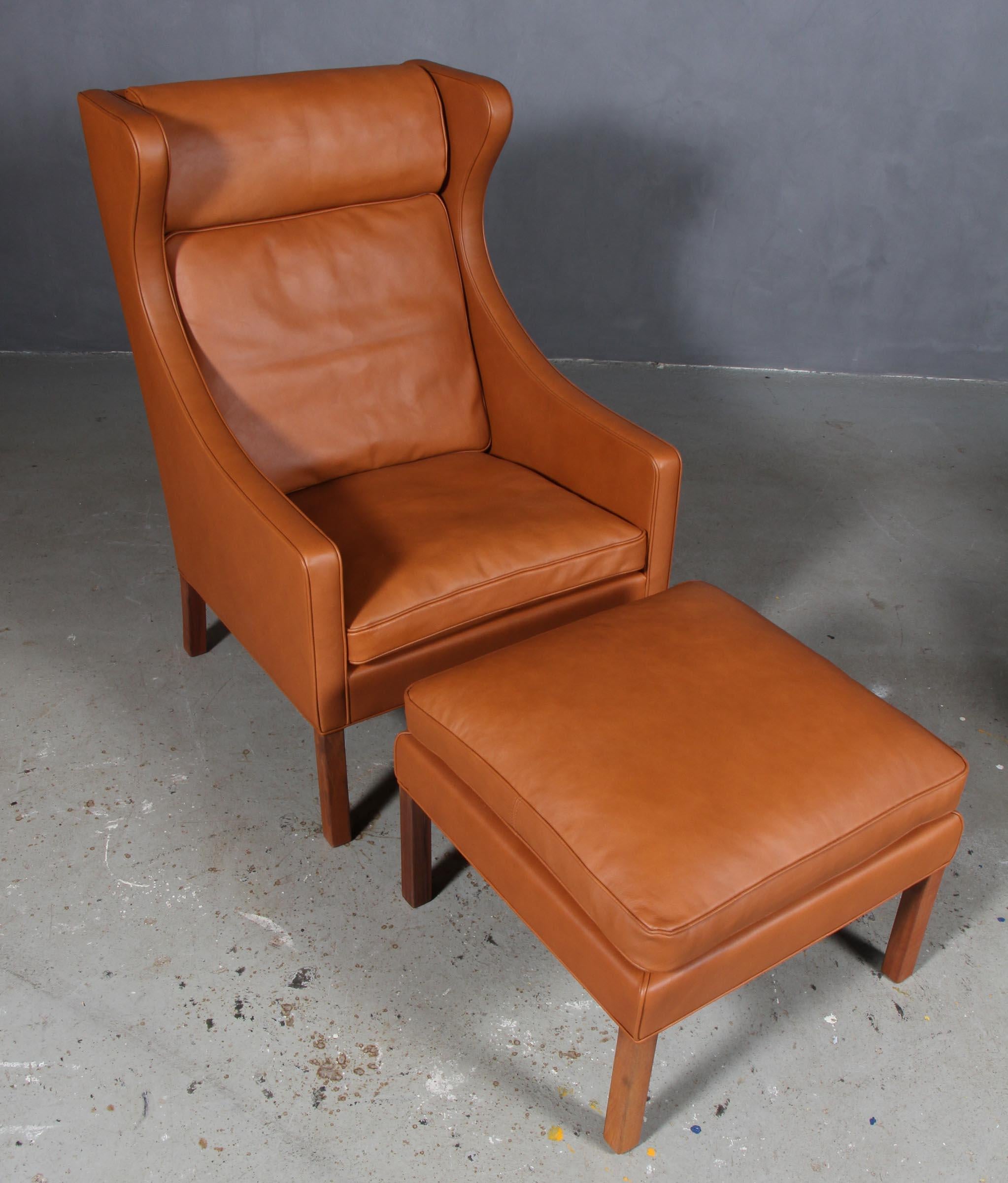 Børge Mogensen wingback chair with ottoman new upholstered with walnut elegance leather.

Legs in teak.

Model 2204, made by Fredericia Furniture.