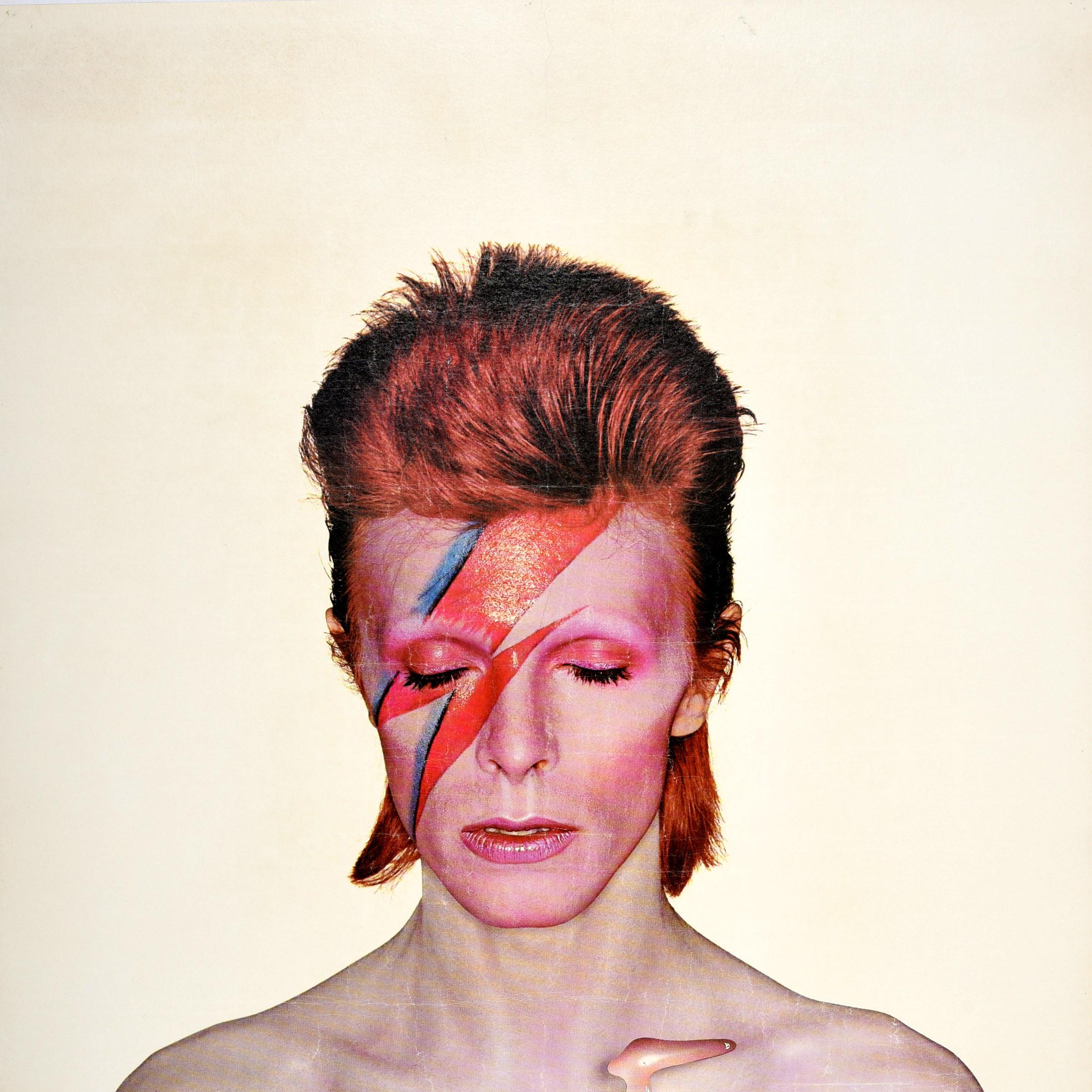 Original vintage music advertising poster for the David Bowie album Aladdin Sane released in 1973 featuring the iconic cover artwork by the English photographer Brian Duffy (1933-2010) of Bowie with red hair and his eyes closed, a red and blue