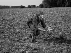 A black and white surreal image of a man in the field holding a metal pyramid