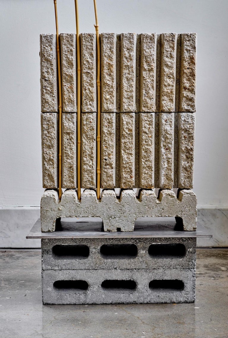 In this piece, two breeze blocks stacked on top of one another make the base of the sculpture. On top of these breeze blocks is a flat, rectangular steel plate. On top of the steel plate are three corrugated concrete blocks. The bottom-most