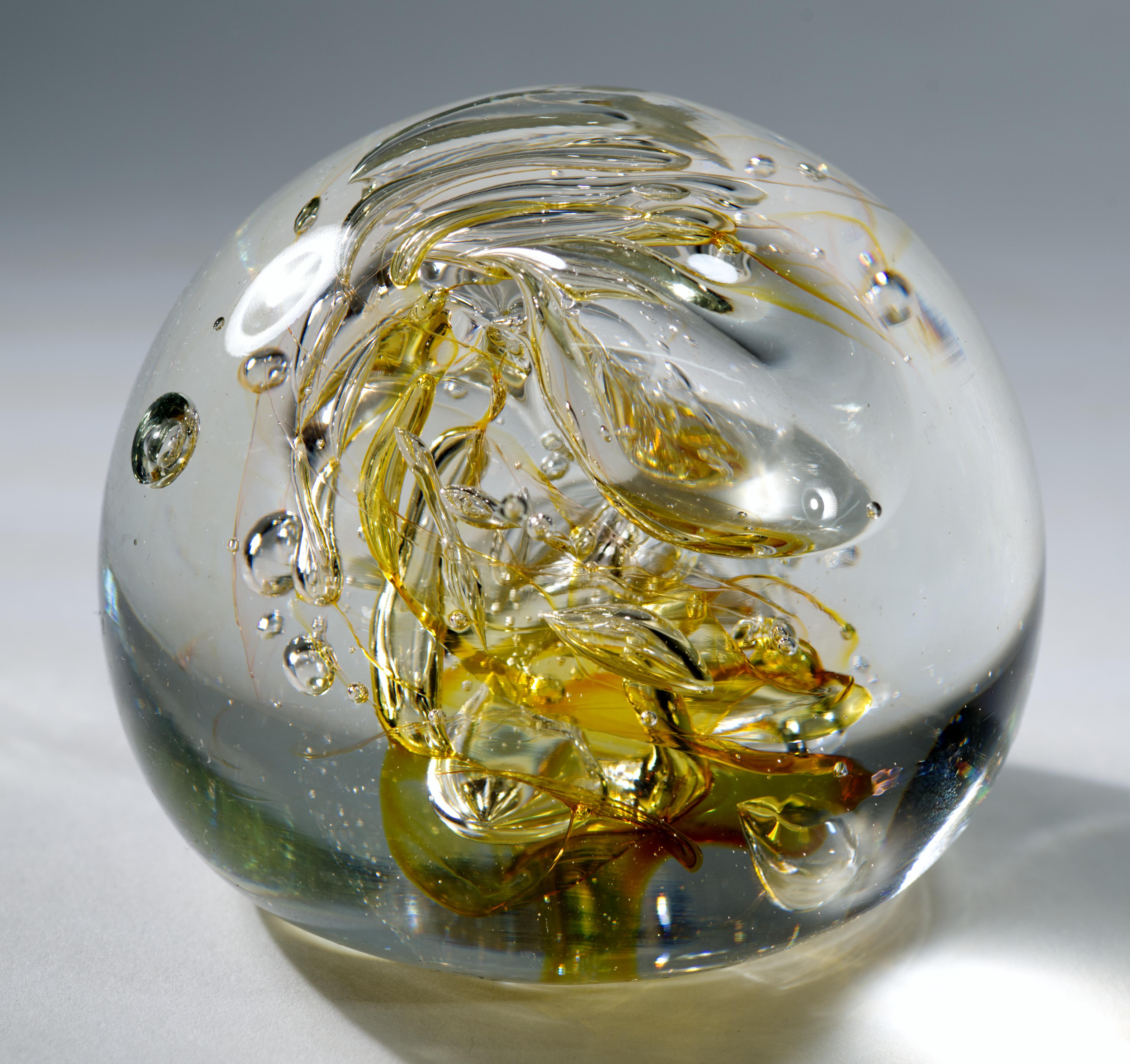  Ce presse-papier sculptural en verre d'art vintage présente un noyau central de verre ambré clair s'écoulant librement et des bulles contrôlées, entourées de verre clair selon la technique sommerso. Les surfaces réfléchissantes des bulles d'air