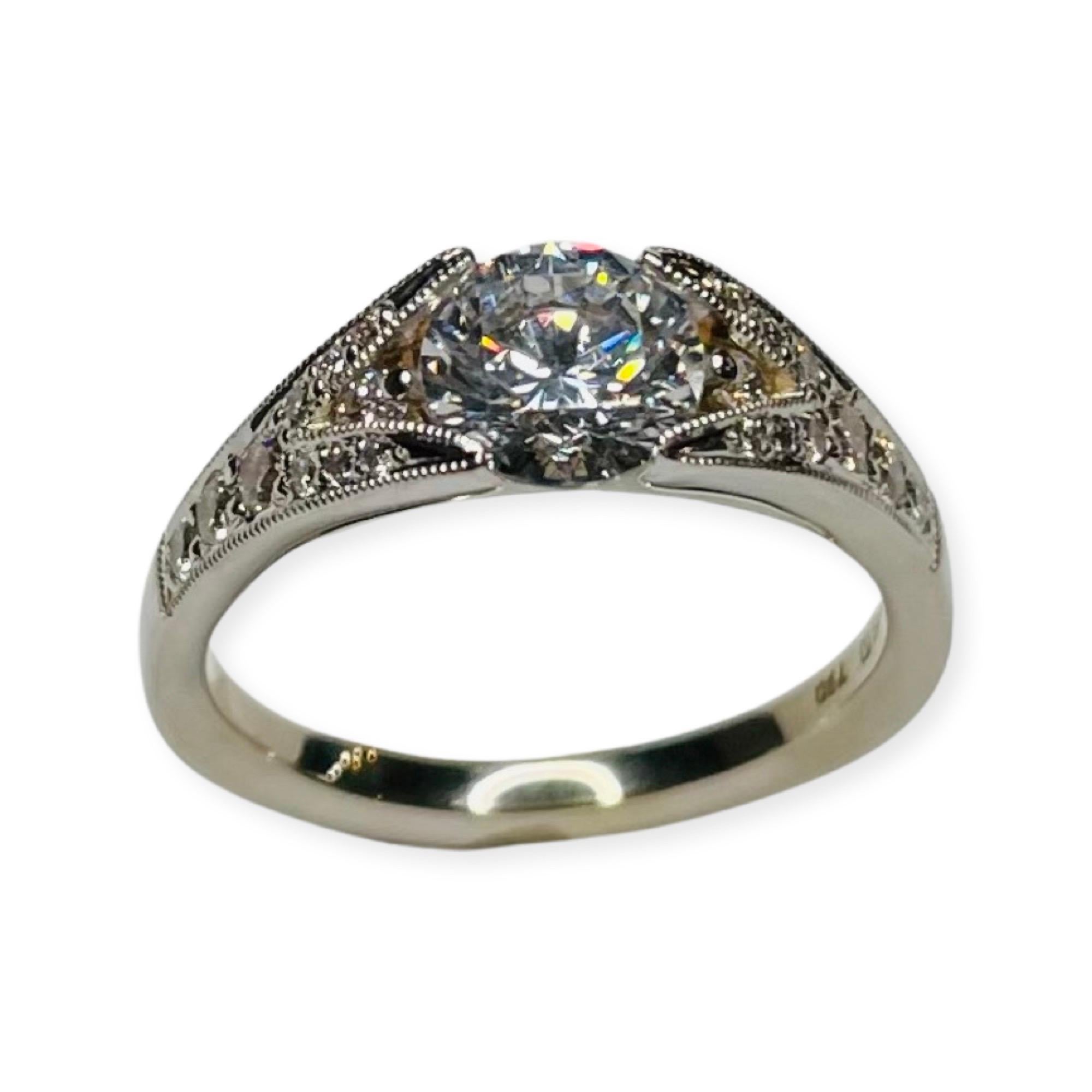 Brian Sholdt 18K White Gold Engagement Ring. It has a 1.0 carat cubic zirconia set in 4 prongs in the center. This CZ is equivalent in size to a 1.0 carat diamond. The CZ center can be replaced with a natural or lab created diamond, colored stone or