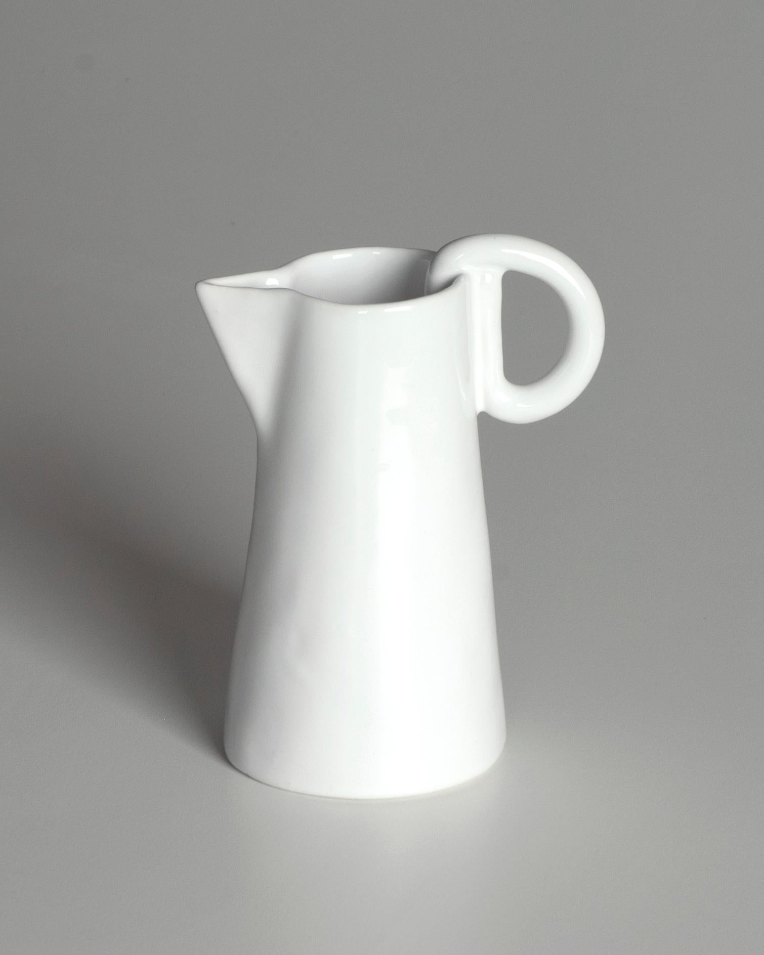 Délicate cruche en céramique blanche, entièrement fabriquée à la main. L'émaillage, appliqué selon la technique du trempage, confère au pot une élégance simple et un caractère unique.