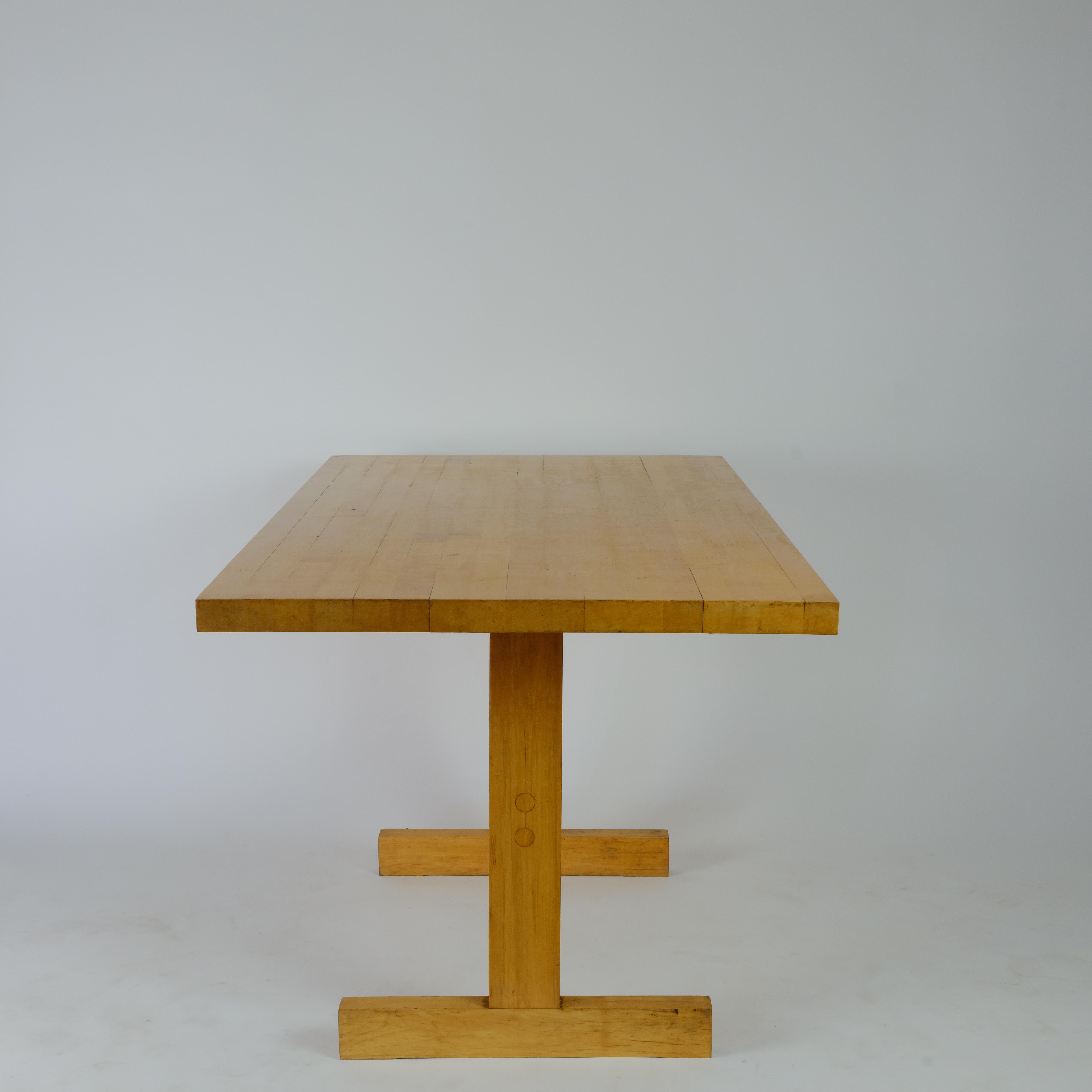 Dining table with strong lines.
Bridge leg and butcher block top doweled through.

Closest resemblance is the Les Arcs table by Perriand minus the metal hardware.

Condition is as see, signs of use are present.