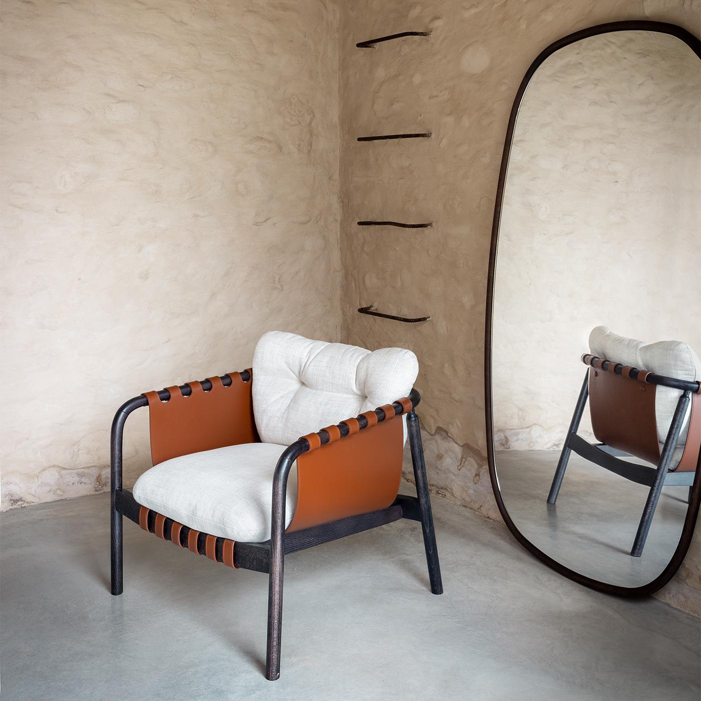 El sillón Bridge combina la piel hecha a mano con un armazón tubular de madera y suaves cojines de tela para lograr una armoniosa mezcla de materiales y texturas. Con un equilibrio entre forma, funcionalidad y comodidad, su atractivo diseño se