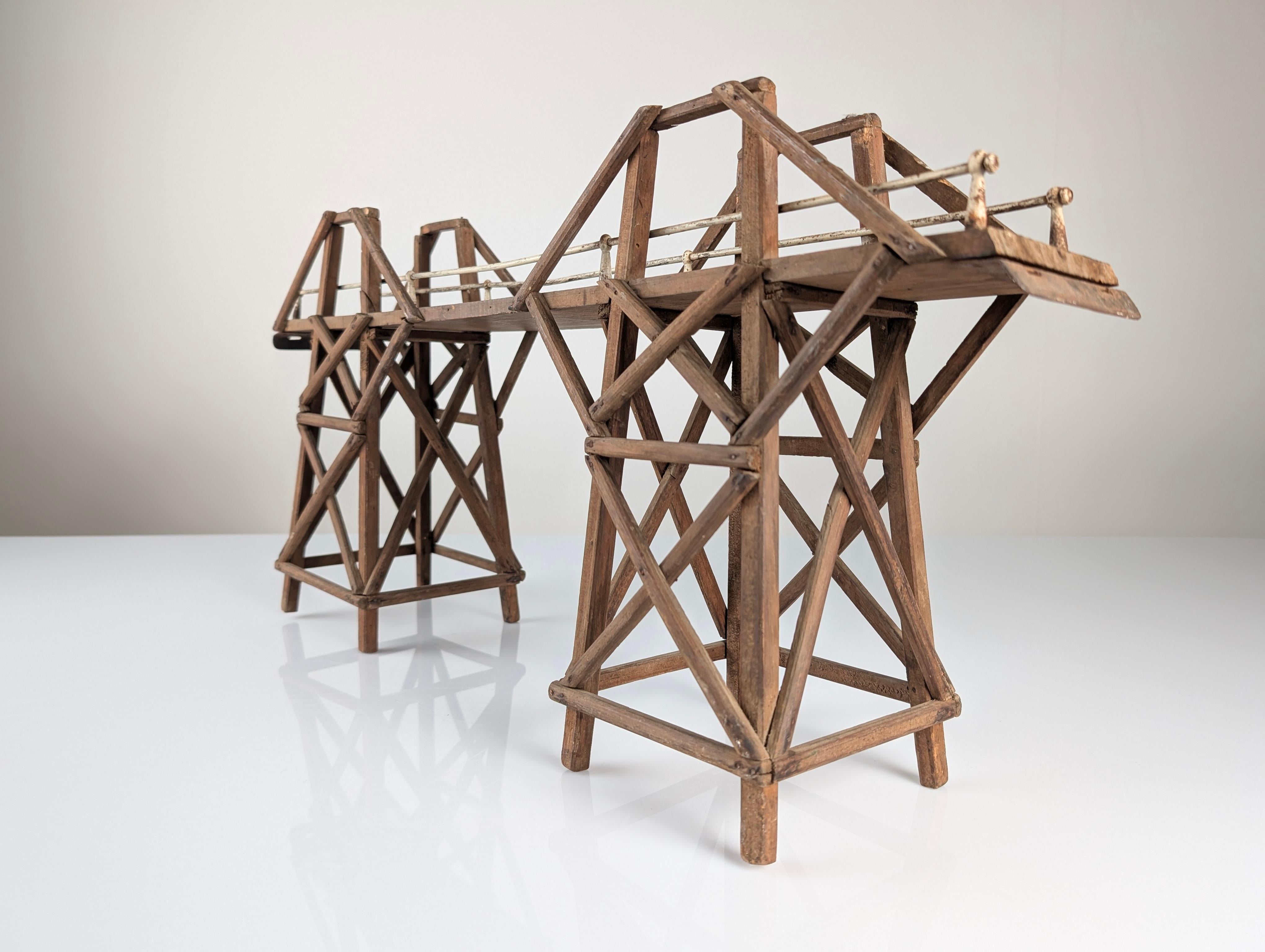 Maquette de l'emblématique pont sur la rivière Kwai, une représentation en bois avec des rambardes en fer qui évoque la monumentale structure d'origine construite pendant la Seconde Guerre mondiale. Le design méticuleux capture l'essence de