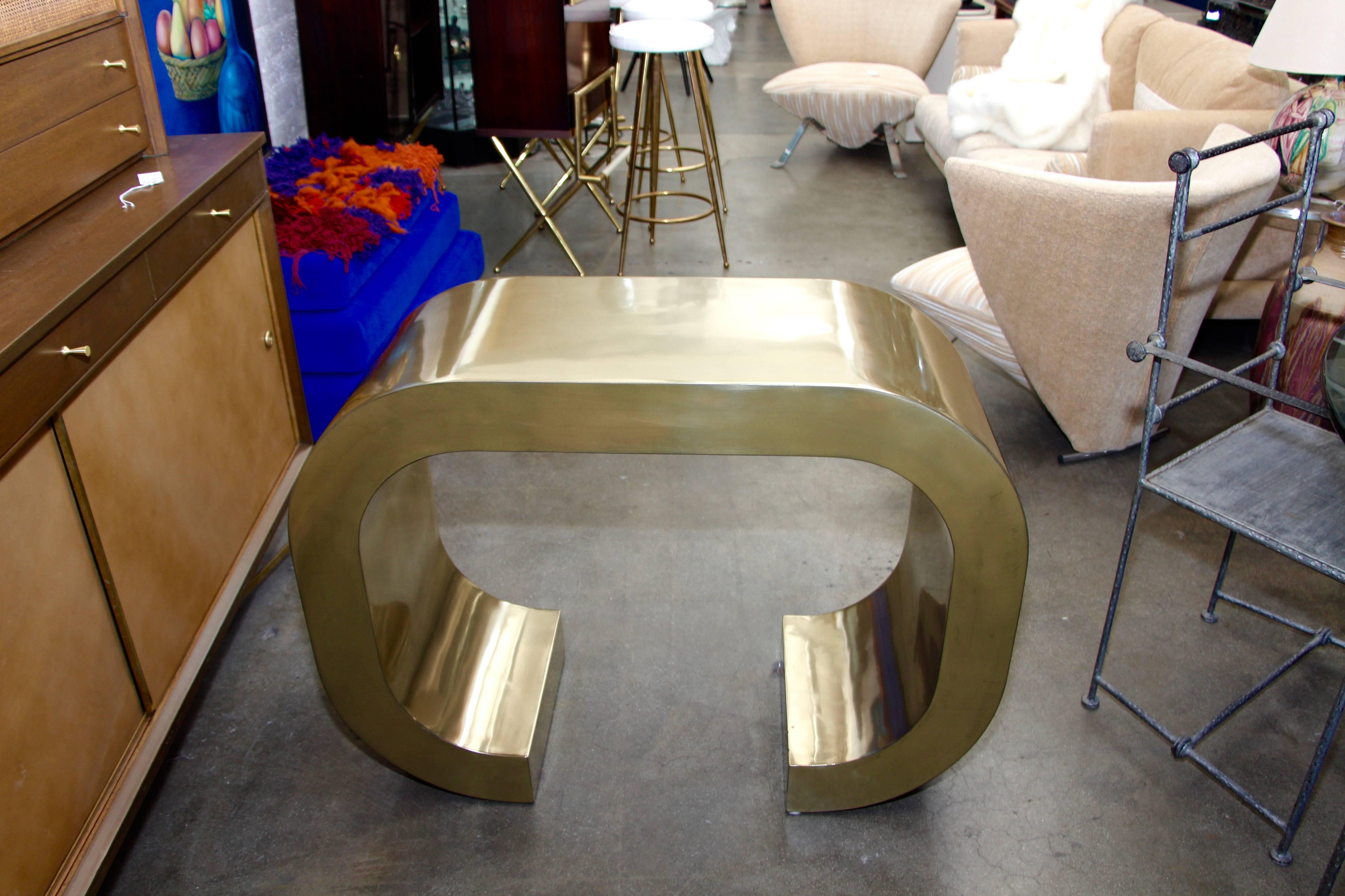 A pretty c shaped console by British over Time Originals. This is a unique one of a kind Prototype custom built. It is coated in Brass and Clear Coated. Designed by Bridges over Time and created by Marco Antonio.   A few minor dings which are