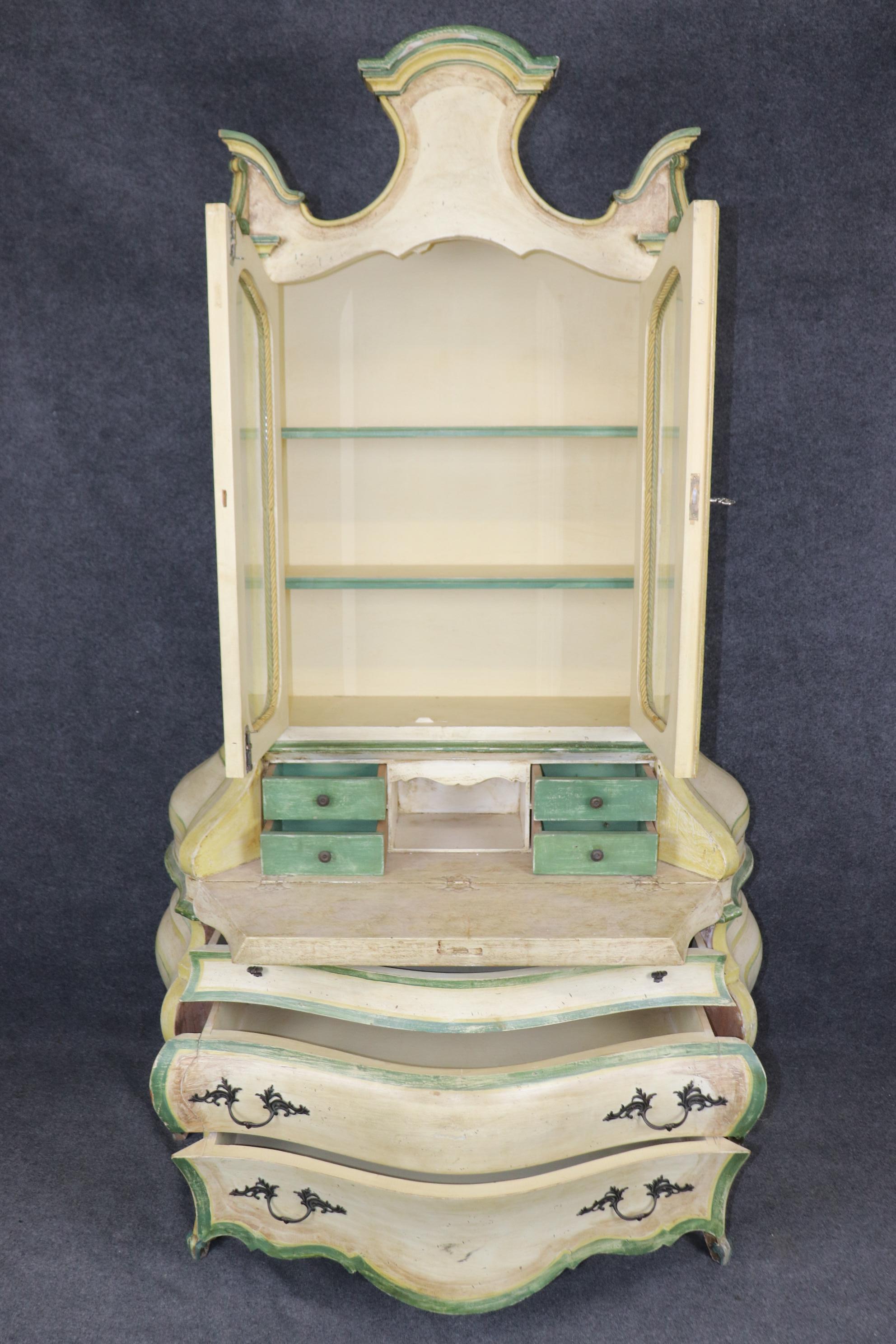 This is a stunning and absolutely charming bright creme and green trimmed paint decoration. The interior reveals cubbies and a nice patina from age to both the case, the interior and the bronze hardware. The piece is two pieces. This is a good