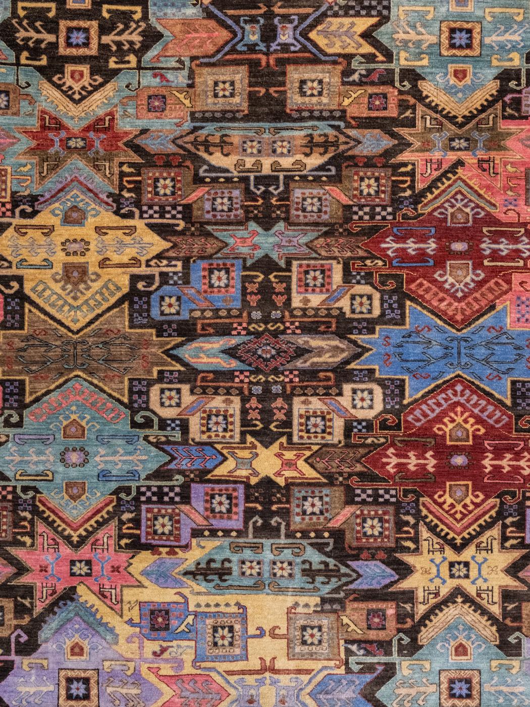 Ce tapis kazakh moderne, noué à la main en pure laine, présente un motif lumineux, coloré et géométrique de 7'11'' x 9'7''. Illustrant un design traditionnel persan kazak, des fleurs géométriques et des motifs de papillons sont détaillés dans des