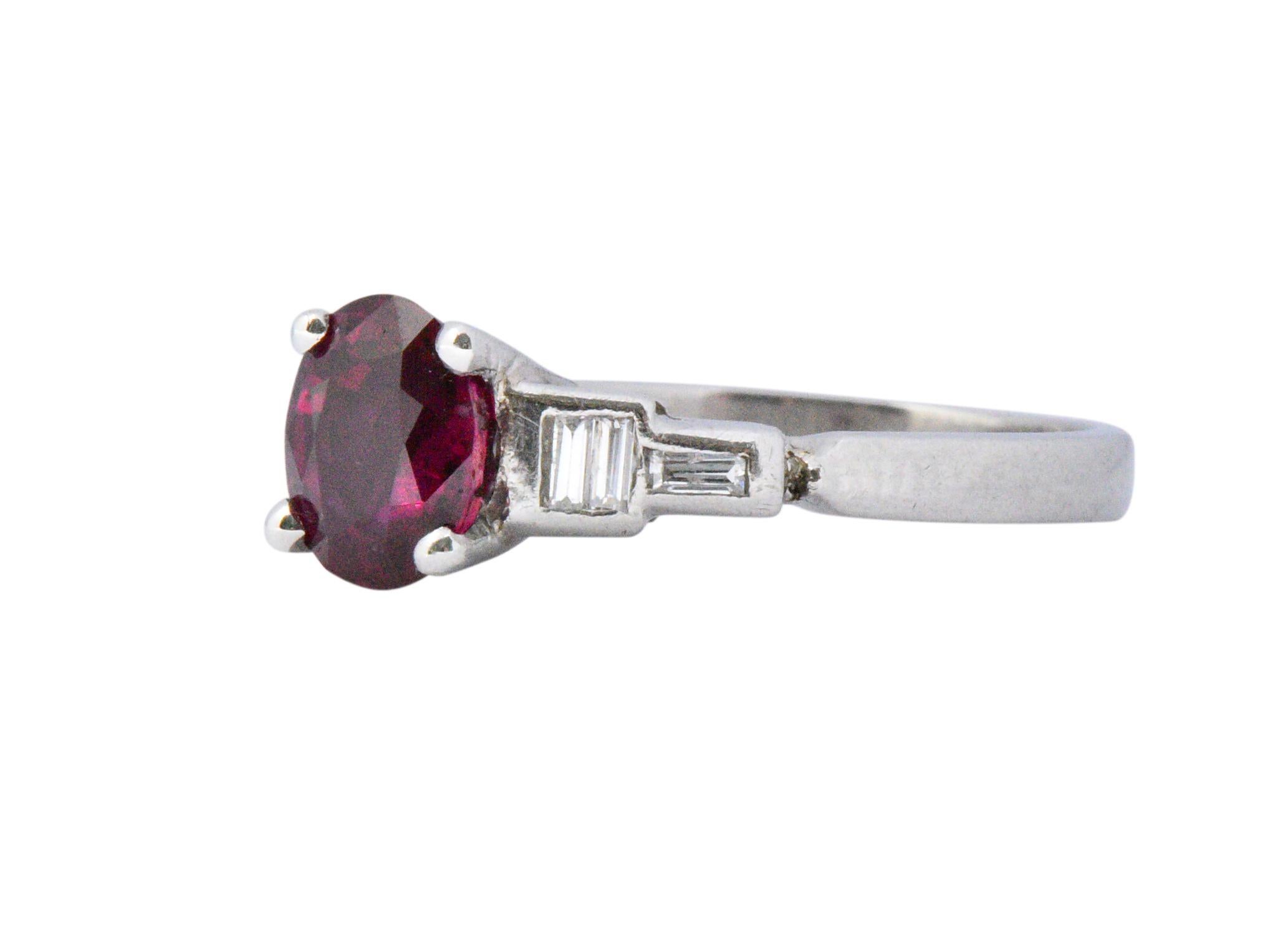 Centering a basket set oval cut ruby weighing approximately 1.51 carats; medium-dark and very slightly purplish-red in color

Flanked by channel set baguette cut diamonds weighing approximately 0.10 carat total; G/H color with VS to I clarity

1.61