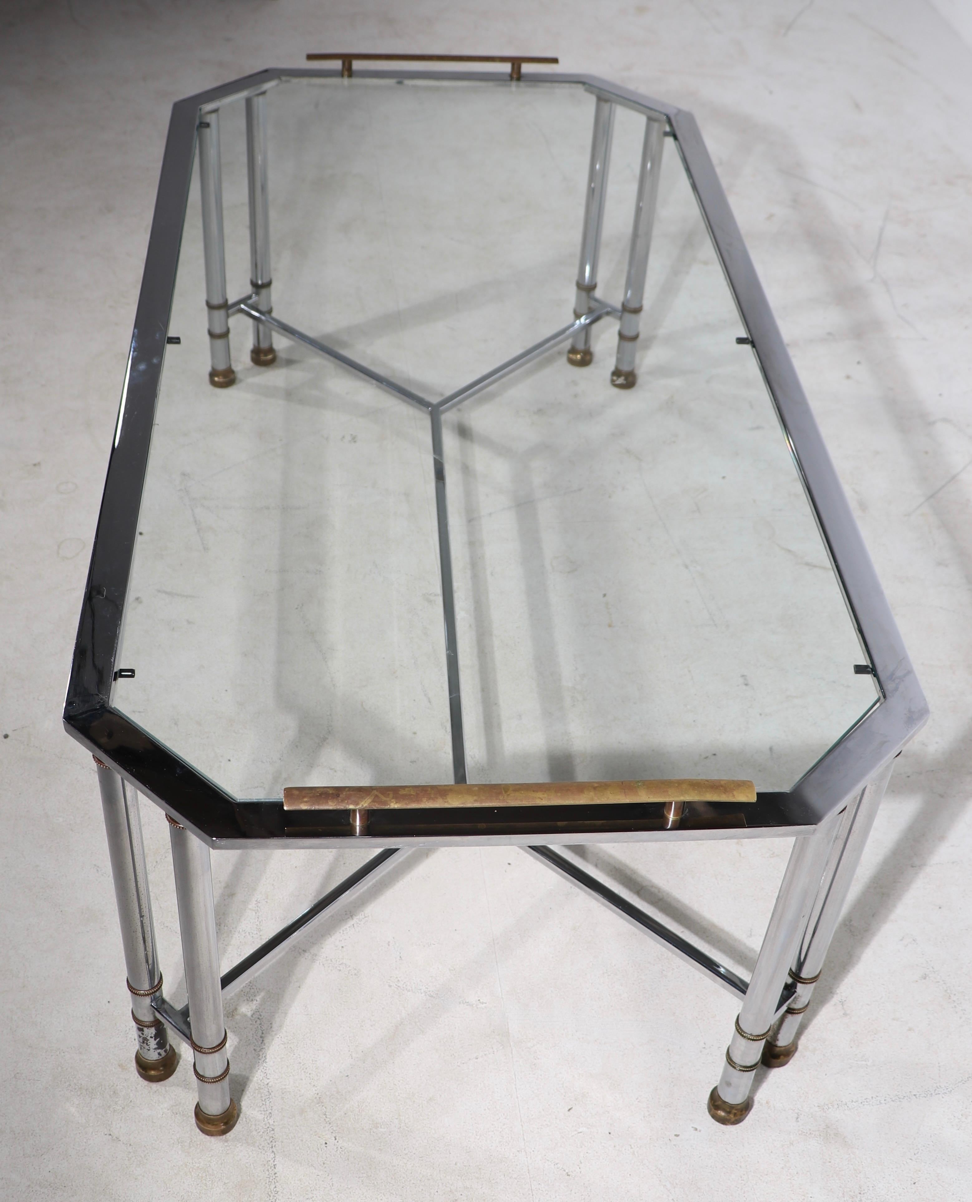 High style chrome, brass and glass coffee table, having a eight sided top, with decorative brass handles. The table surface is 15 in. x total H inc handles 17 in. The chrome frame shows minor cosmetic wear, notable on one foot ( see images ) and the