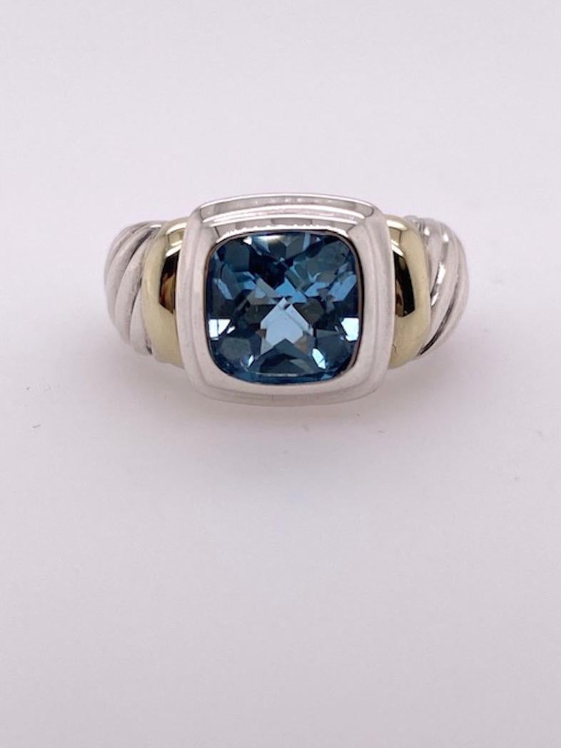 Very bright and attractive ring.  Made and signed by DAVID YURMAN.  The center is a large faceted blue topaz, with brilliant color.  Set in a sterling silver band with 14K yellow gold accents on the sides. Size 6 1/2 and can be custom-sized.

Alice