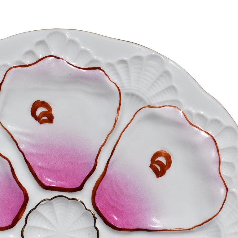 Grand Millenials will love this pretty pink oyster dish. Round with scalloped edges, this piece features 6 wells for oysters and a center well for butter. Each well is hand painted in gold, with a bright ombre pink at the center. Raised shell design