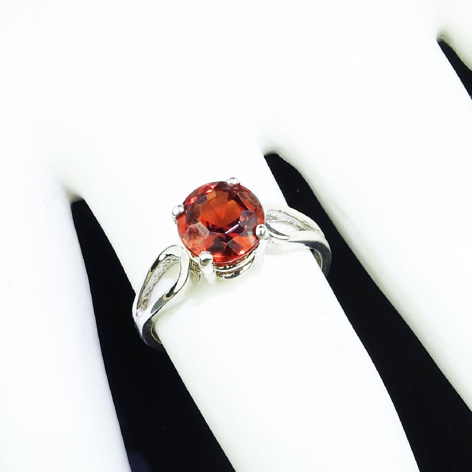 Custom made, Sterling Silver Ring with Round Spessartite Garnet of 2.16ct. Unique, sparkling orangy brown typical  Spessartite. The Sterling Silver setting is an elongated tear drop on either side of the basket holding the garnet. Size 7. No changes