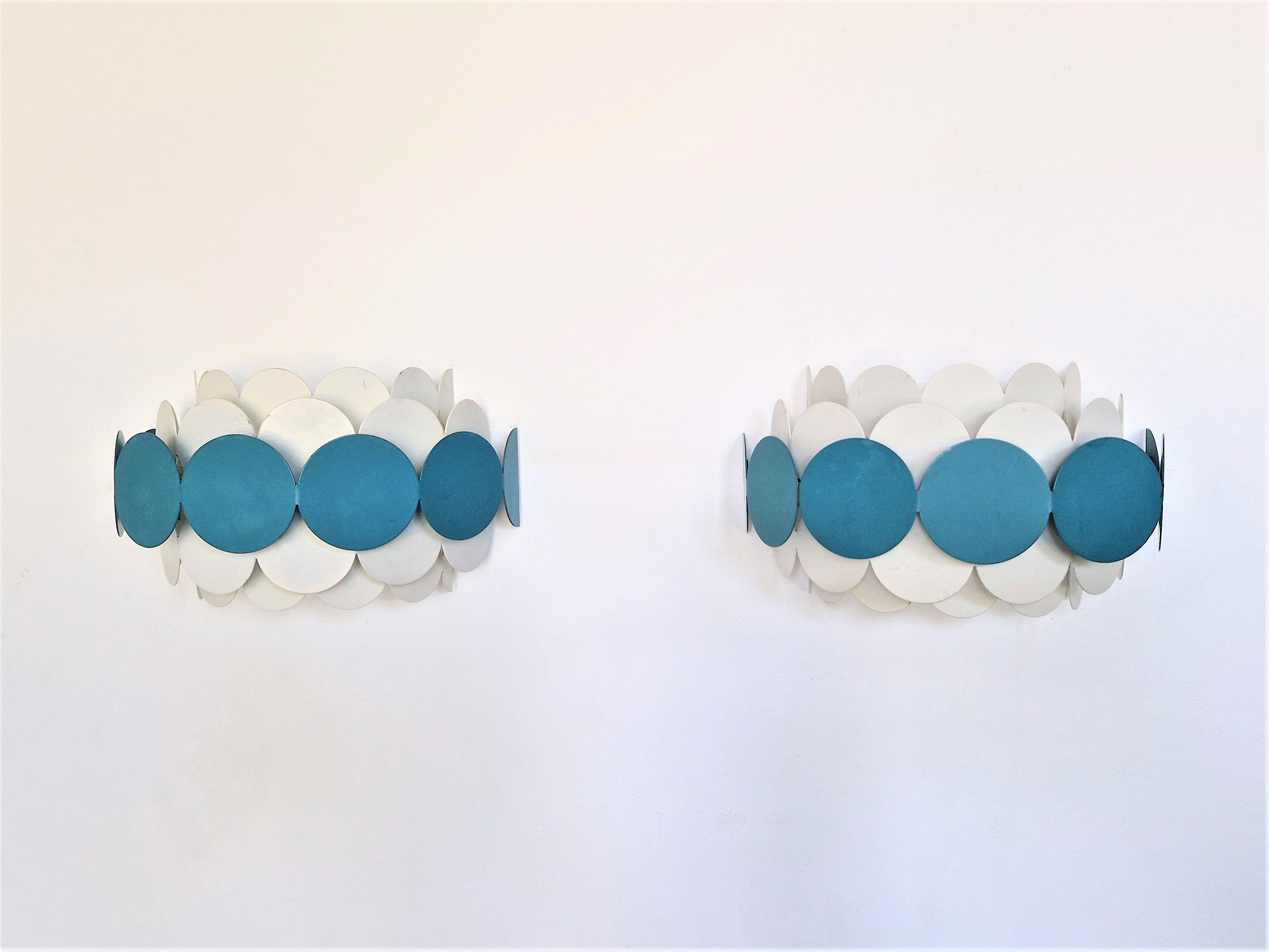 These wall lights are manufactured by Doria Leuchten in the late 1960's or 1970's. They consist out of layers of white and bright petrol blue metal strips. Both lights have a pulling cord so these can nicely be used as bedside lamps for example. The