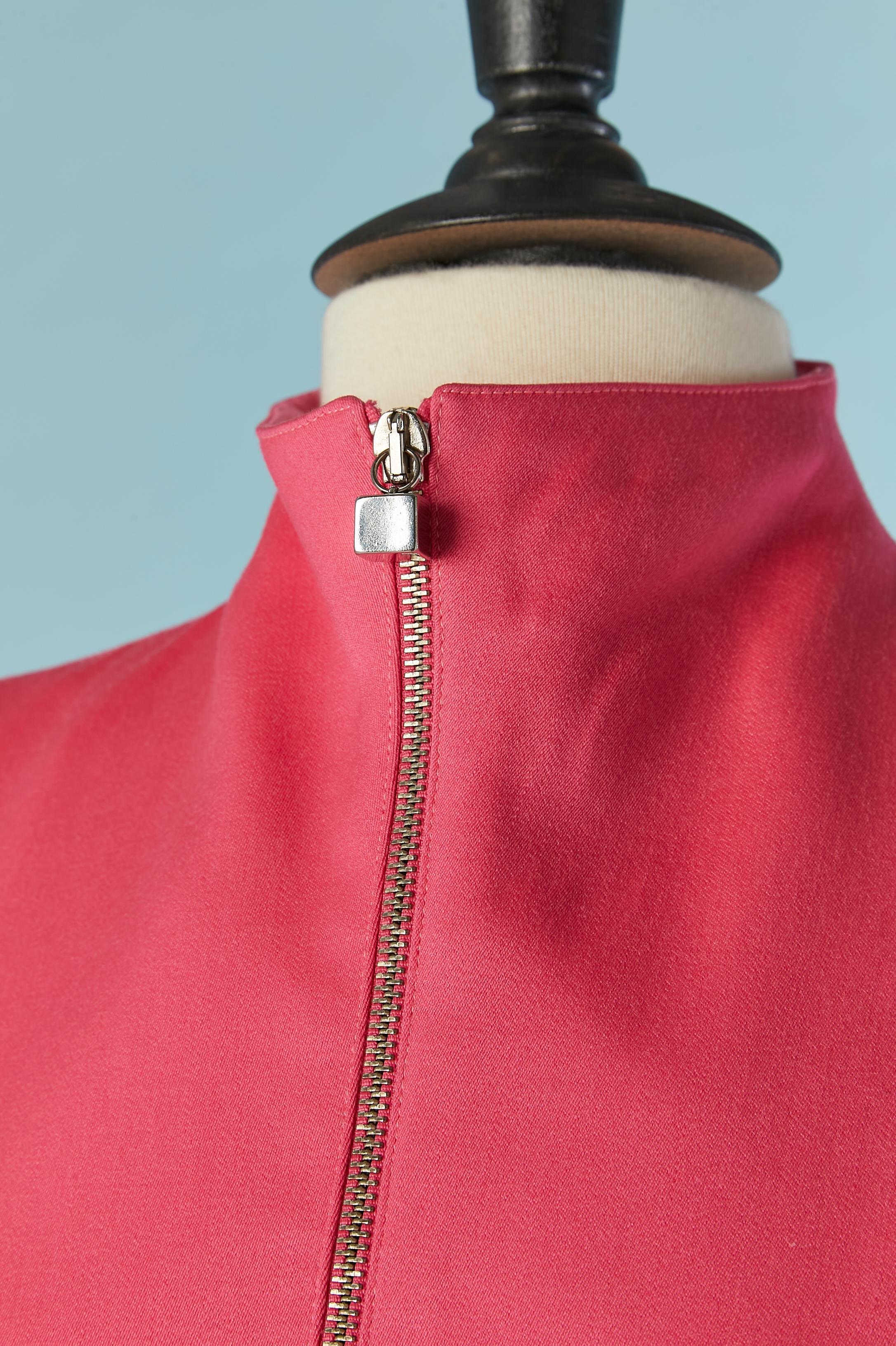 Giacca in ping brillante con chiusura a zip al centro della parte anteriore. L'etichetta del tessuto è stata tagliata, ma il tessuto principale è lana e la fodera probabilmente rayon. Bottoni metallici quadrati e asola sui polsini. 
Spallacci. Zip