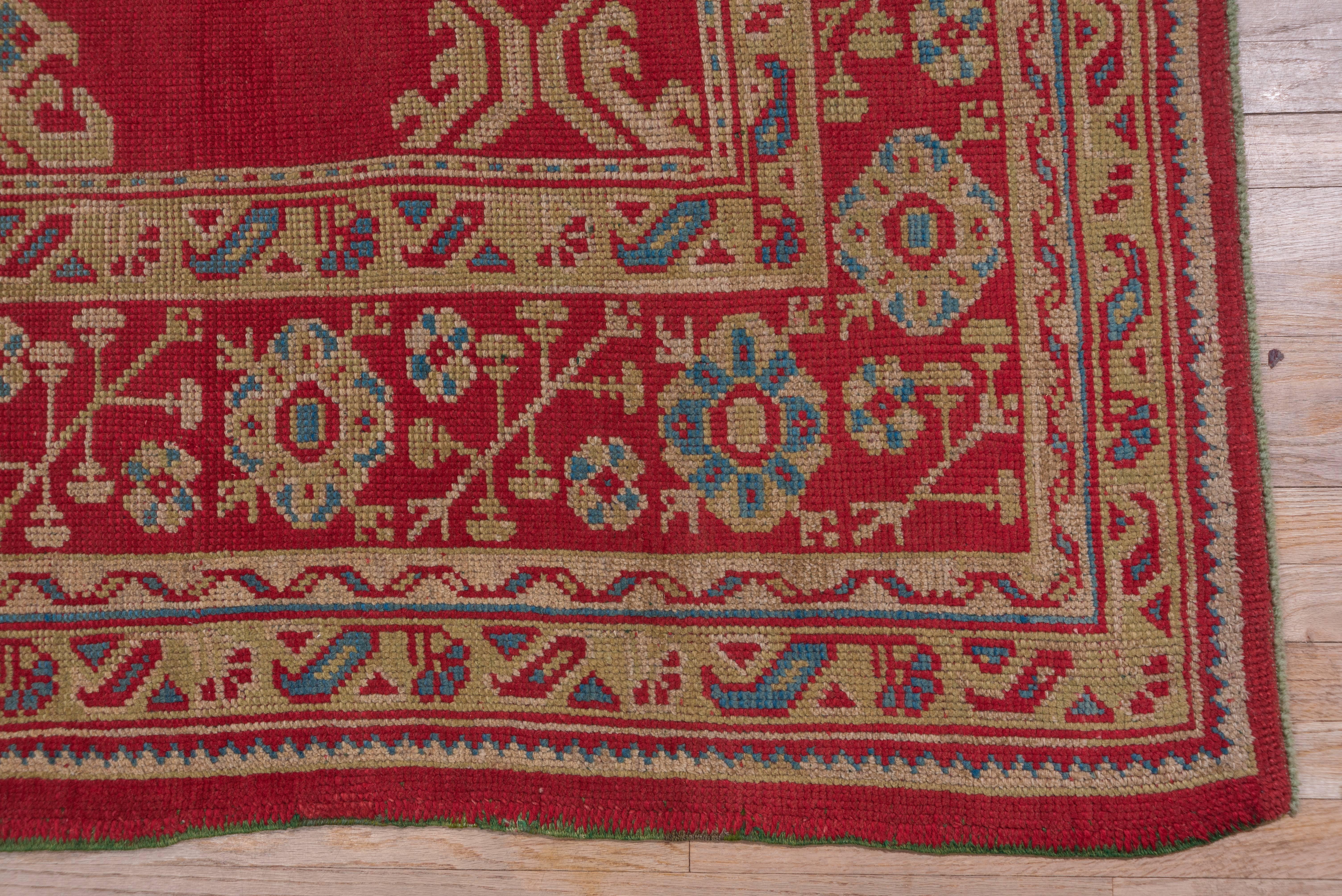 This 'Turkey Red' west Anatolian town carpet has a Yaprak and palmette pattern derived from 18th century archetypes. The red hyacinth and octagon rosette border also has earlier sources. Light yellow and green are among the detail tones.