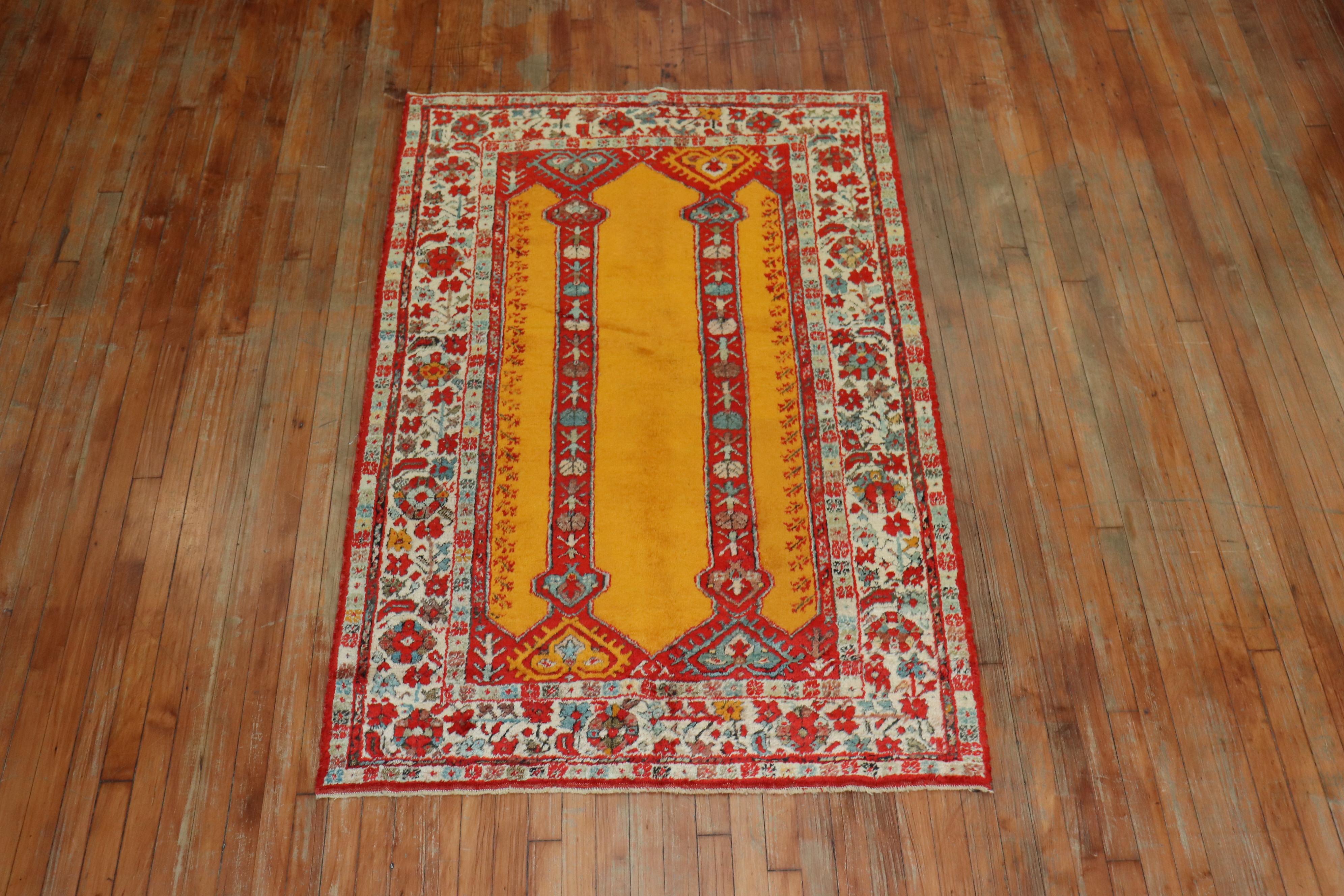 An early 20th century angora wool Oushak rug with a bright saffron color field with a double scroll column prayer motif. This is a genuine piece woven with angora goat wool and it’s an antique. There is no noticeable repairs or any condition issues
