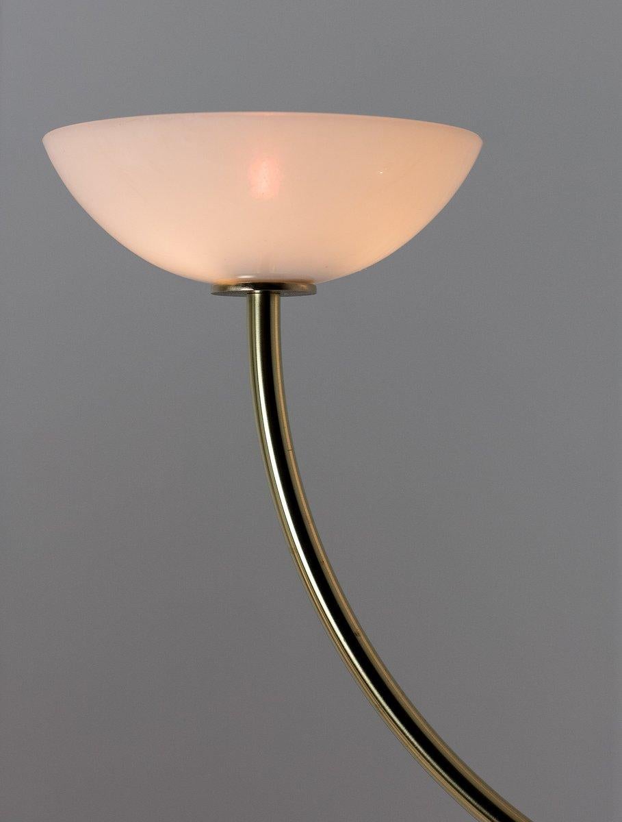 Two domed glass shades are balanced on the ends of a carefully bent brass arc; projecting light upwards while also diffusing light below.