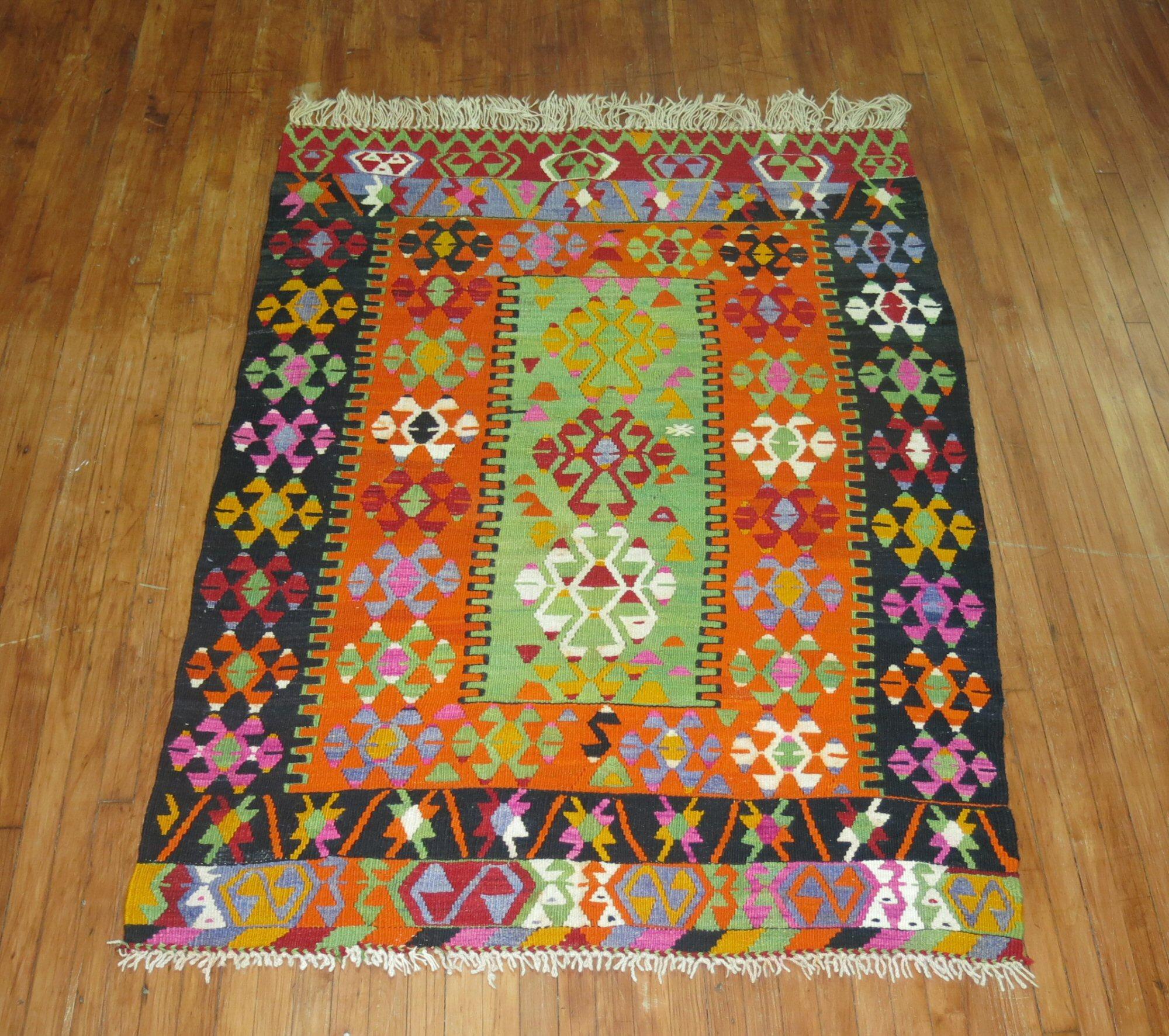 Colorful vintage Turkish Kilim flat-weave from the mid-20th century. Orange and bright green are the dominant colors on this beauty.

Measures: 5' x 6'10”.