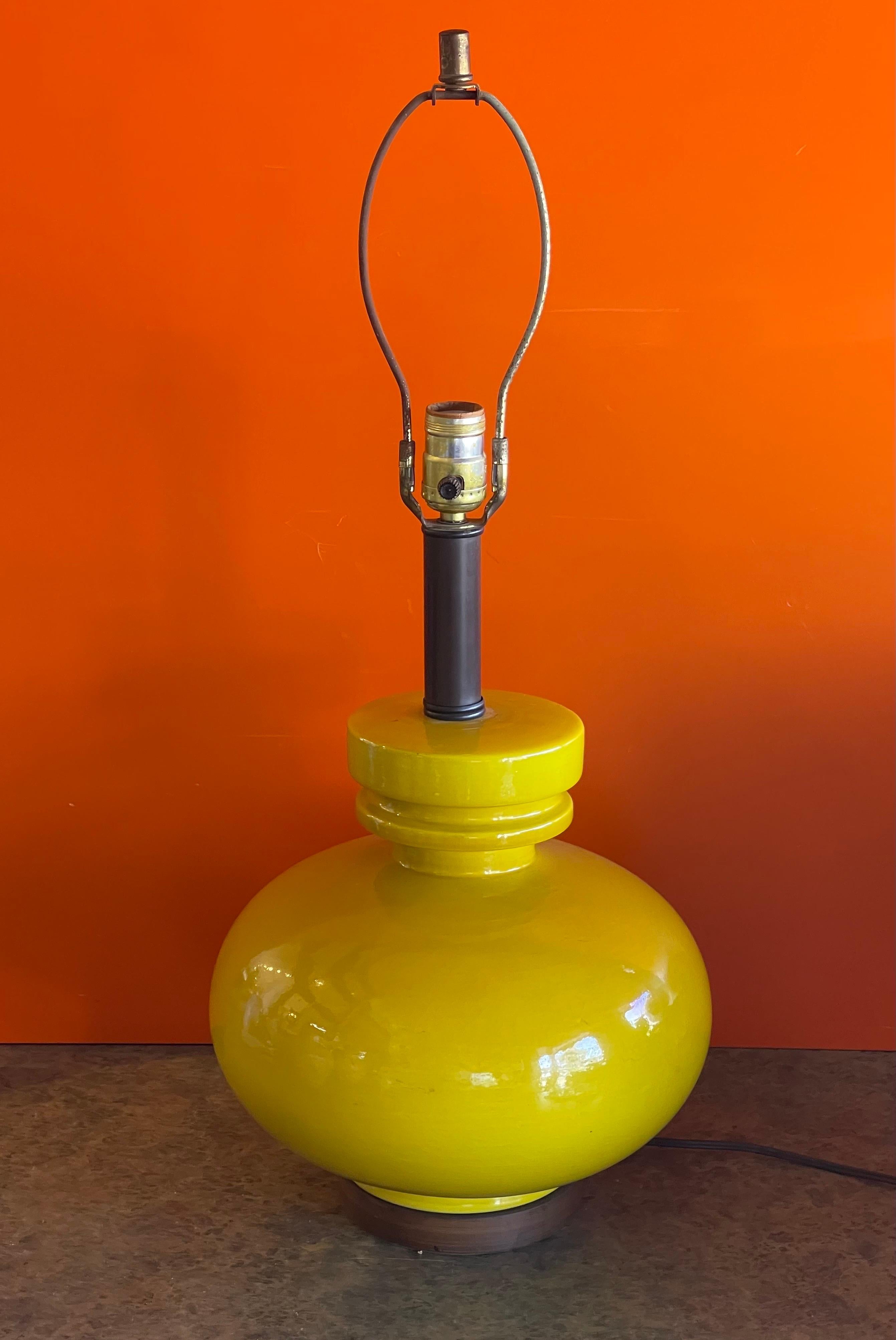A bright yellow glazed ceramic studio pottery table lamp with walnut base, circa 1960s. The lamp measures 11.5