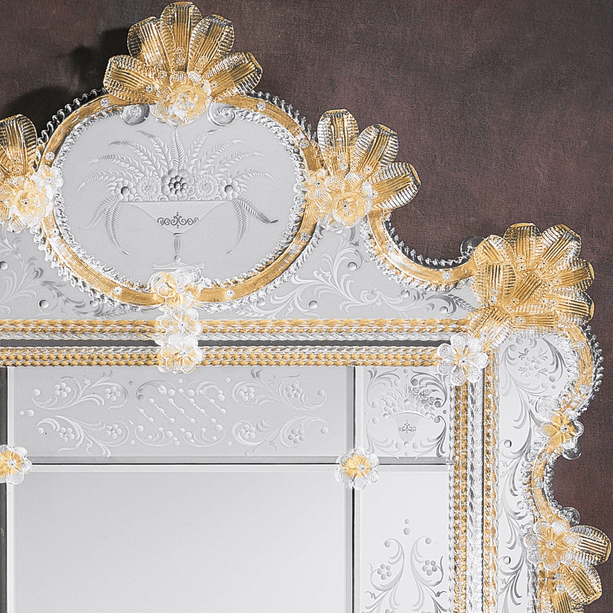 A luxurious Venetian-style mirror made of Murano glass.
Made by the expert hands of Murano glass masters, with a frame formed by crystal rods and curls on a gold background with trimmings of leaves, roses and crystal flowers, the engravings that