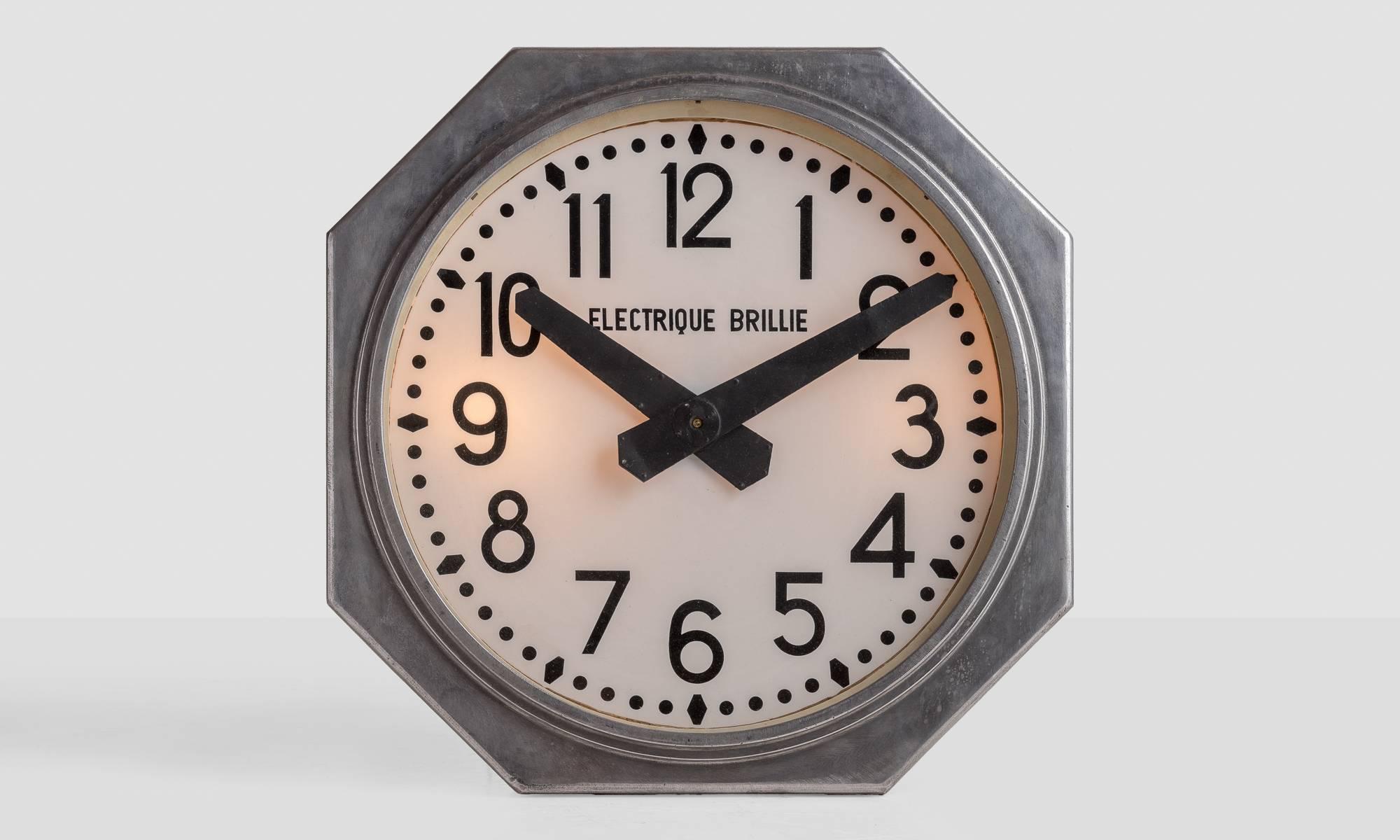 Brillie Electrique railway clock, circa 1950.

Large industrial form in beautifully patinated aluminium with hand-painted numbers and opaline glass face. Electrically powered and illuminated by light set behind clock face.