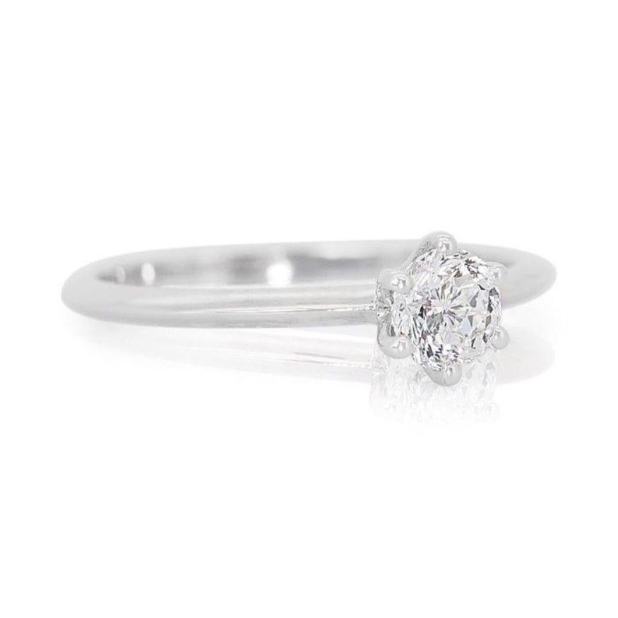 This ring isn't merely an ornament; it's an invitation to embrace life's brilliance, with every facet whispering promises of joy and enduring beauty. At its heart, nestled in 18K white gold, lies a magnificent 0.51-carat round brilliant diamond.