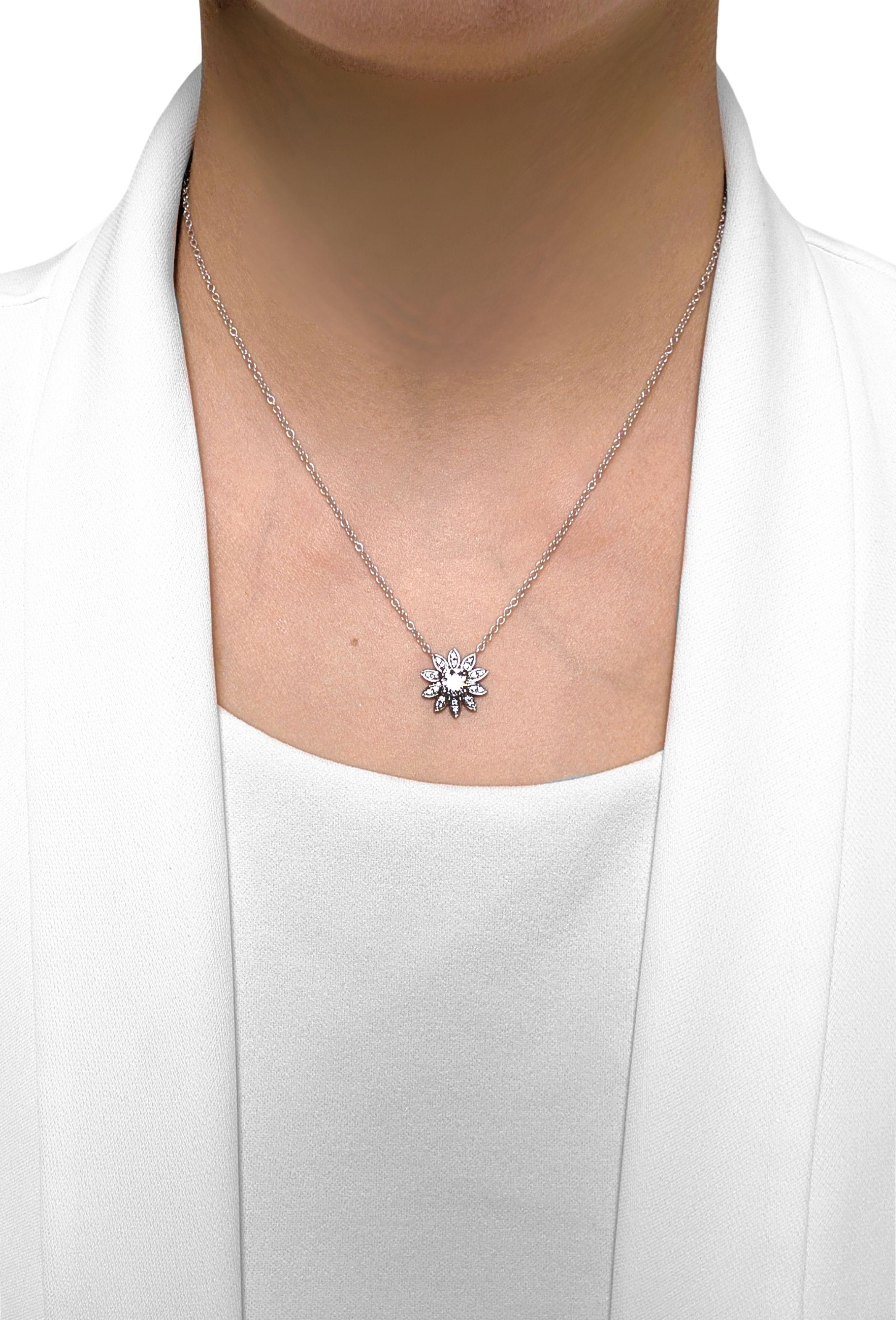 Questa collana certificata GIA è incentrata su un diamante brillante rotondo da 0,61 carati, di colore D e purezza VS1, circondato da 20 diamanti brillanti rotondi (0,14 carati in totale) in una delicata composizione floreale. Tutte le pietre